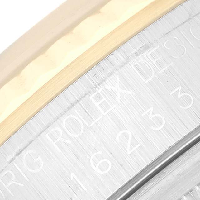 The image shows a close-up of the engraved side of a Rolex Datejust 16233 Men's Steel and Gold (two tone) Silver Dial 16233 Men's Steel and Gold (two tone) Silver Dial watch, focusing on the case and serial number.