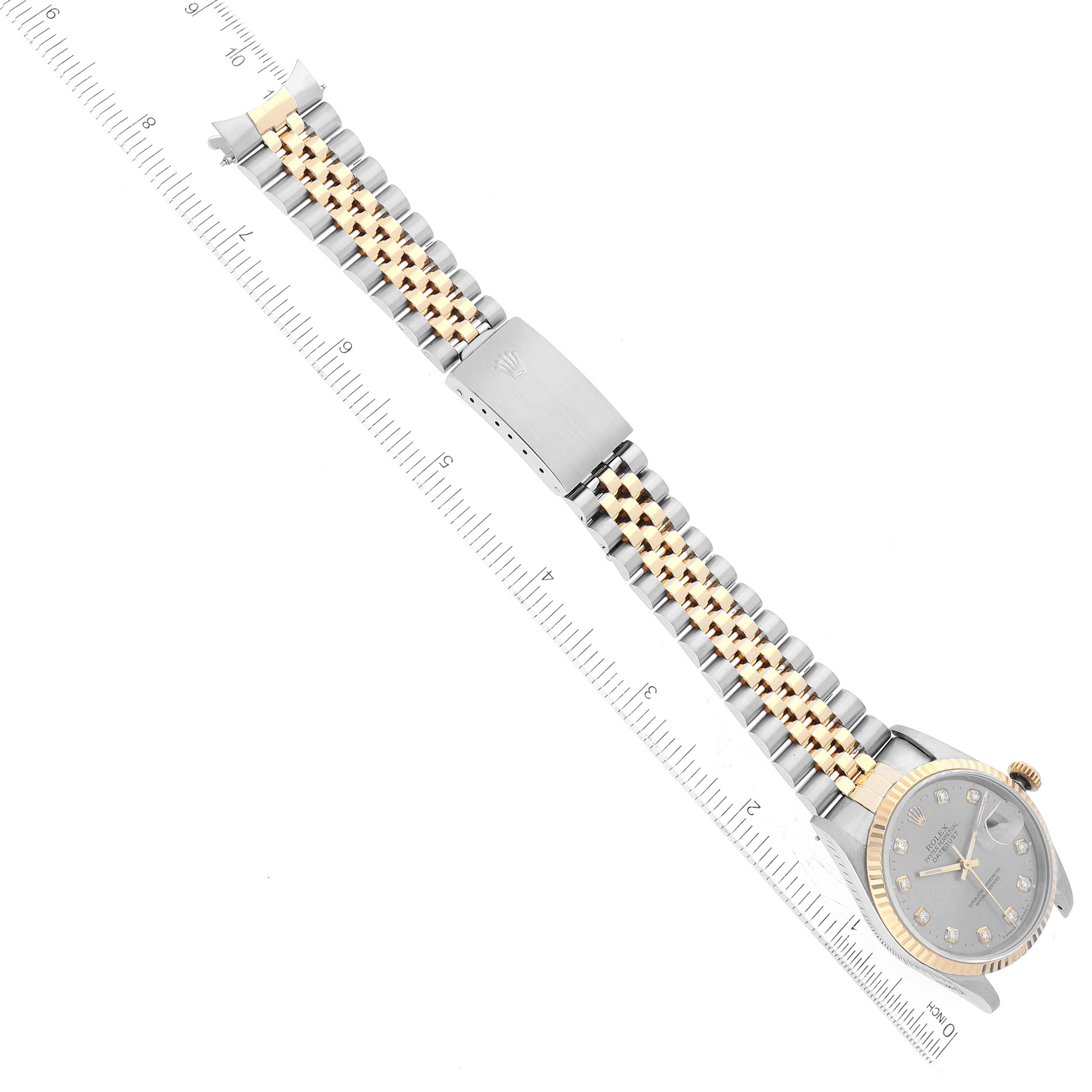 The image shows a Rolex Datejust 16233 Men's Steel and Gold (two tone) Silver Dial 16233 Men's Steel and Gold (two tone) Silver Dial watch laid flat, highlighting its face, band, clasp, and part of a measuring scale.