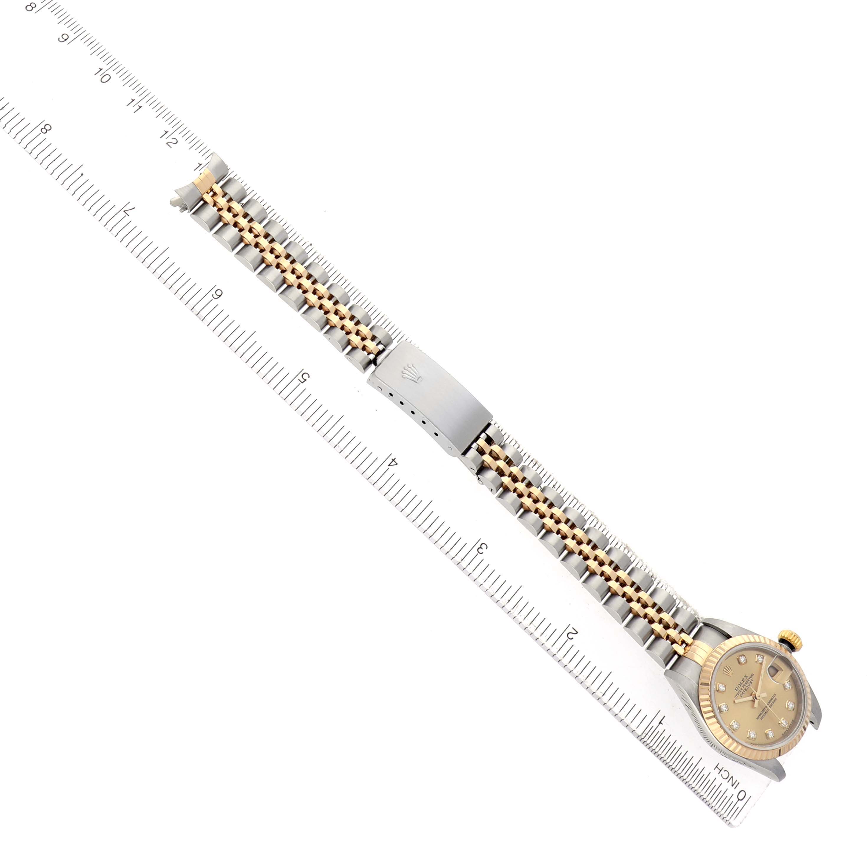 The Rolex Datejust 79173 Women's Steel and Gold (two tone) Champagne Dial watch is shown from an overhead angle, displaying the bracelet and clasp alongside a ruler for scale.