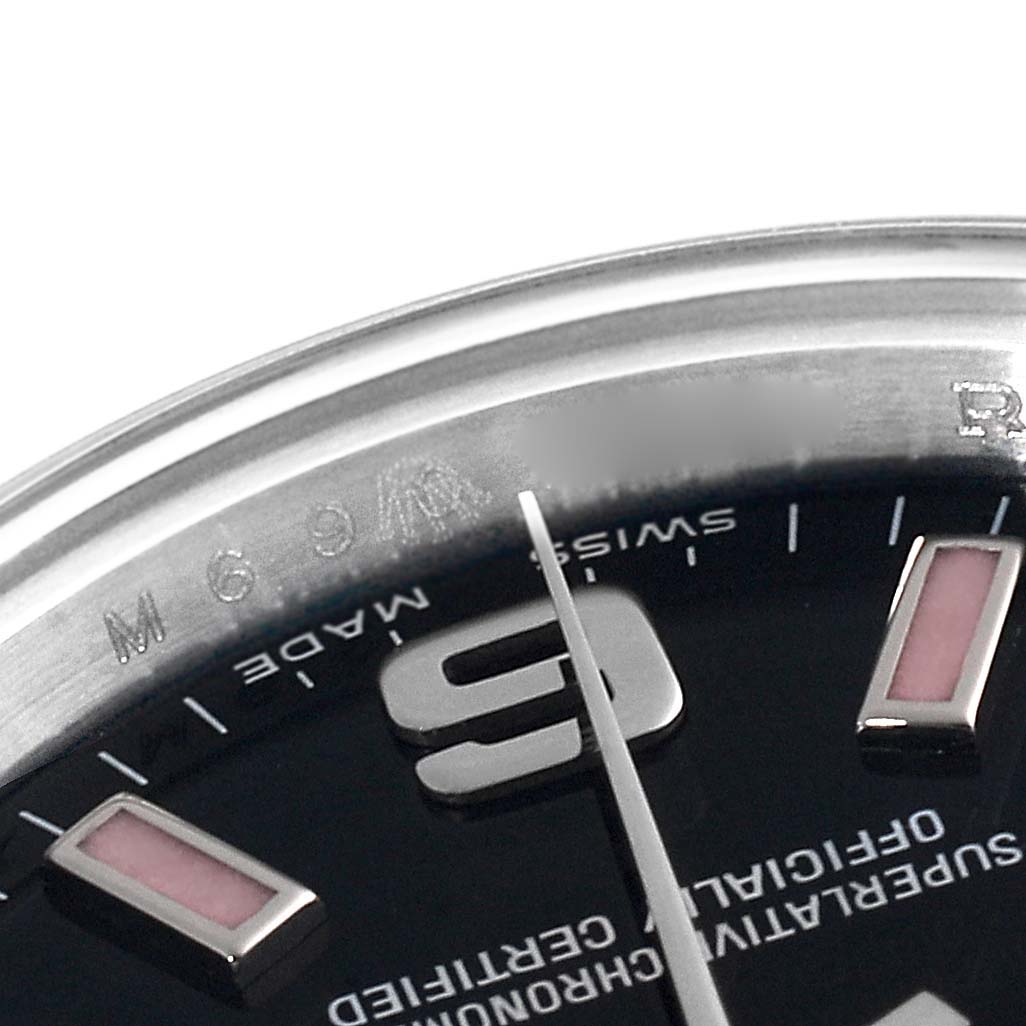This close-up image of a Rolex Oyster Perpetual 176200 Women's Stainless Steel Black Dial 176200 Women's Stainless Steel Black Dial watch shows a portion of the dial, indices, part of the minute hand, and the engraving on the inner bezel.