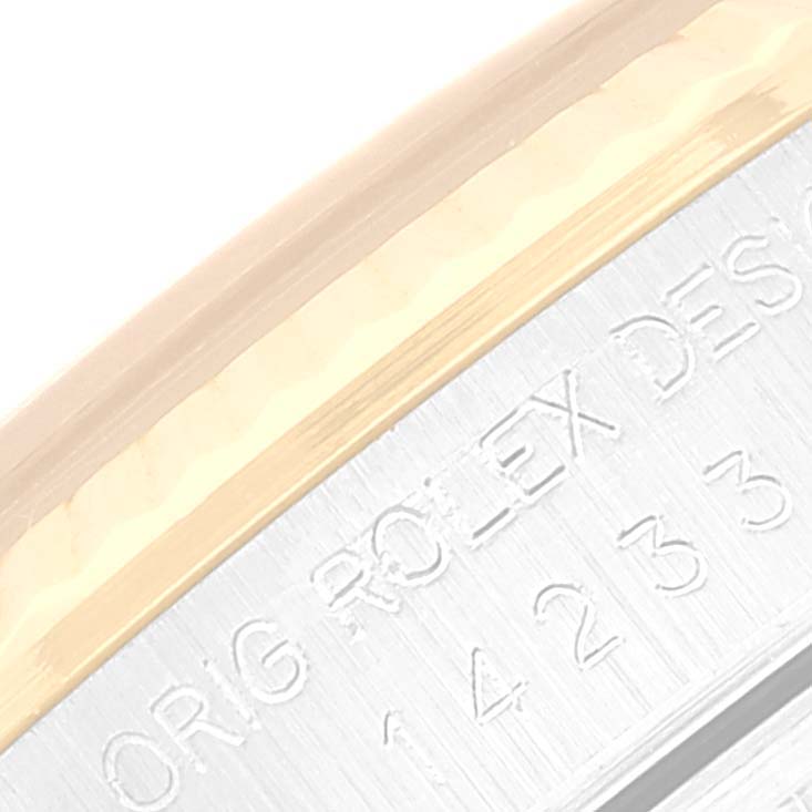 The image shows a close-up of the engraved edge of a Rolex Oyster Perpetual 14233 Men
s Steel and Gold (two tone) Champagne Dial 14233 Men
s Steel and Gold (two tone) Champagne Dial watch case.