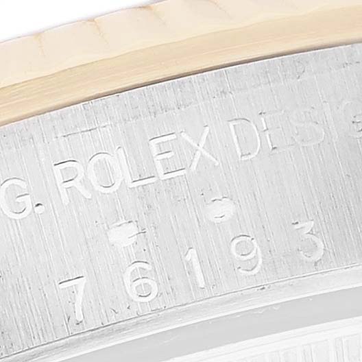 This image shows a close-up angle of the engraved serial number and branding on the bezel of the Rolex Oyster Perpetual 76193 Women's Steel and Gold (two tone) Black Dial 76193 Women's Steel and Gold (two tone) Black Dial watch.