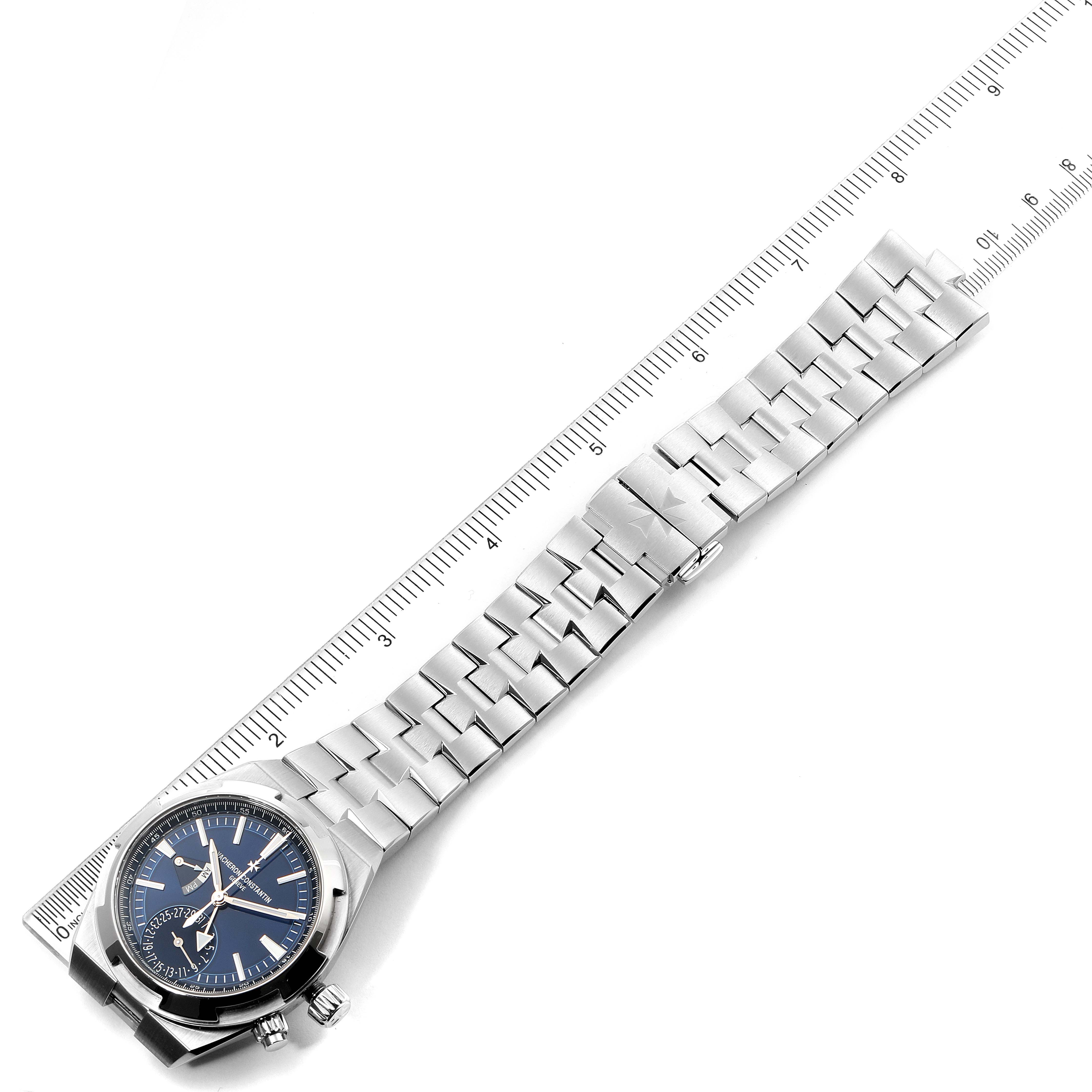 The Vacheron Constantin Overseas 7900V/110A-B334 Men's Stainless Steel Blue Dial 7900V/110A-B334 Men's Stainless Steel Blue Dial model watch is shown lying flat with its metal bracelet fully extended alongside a ruler.