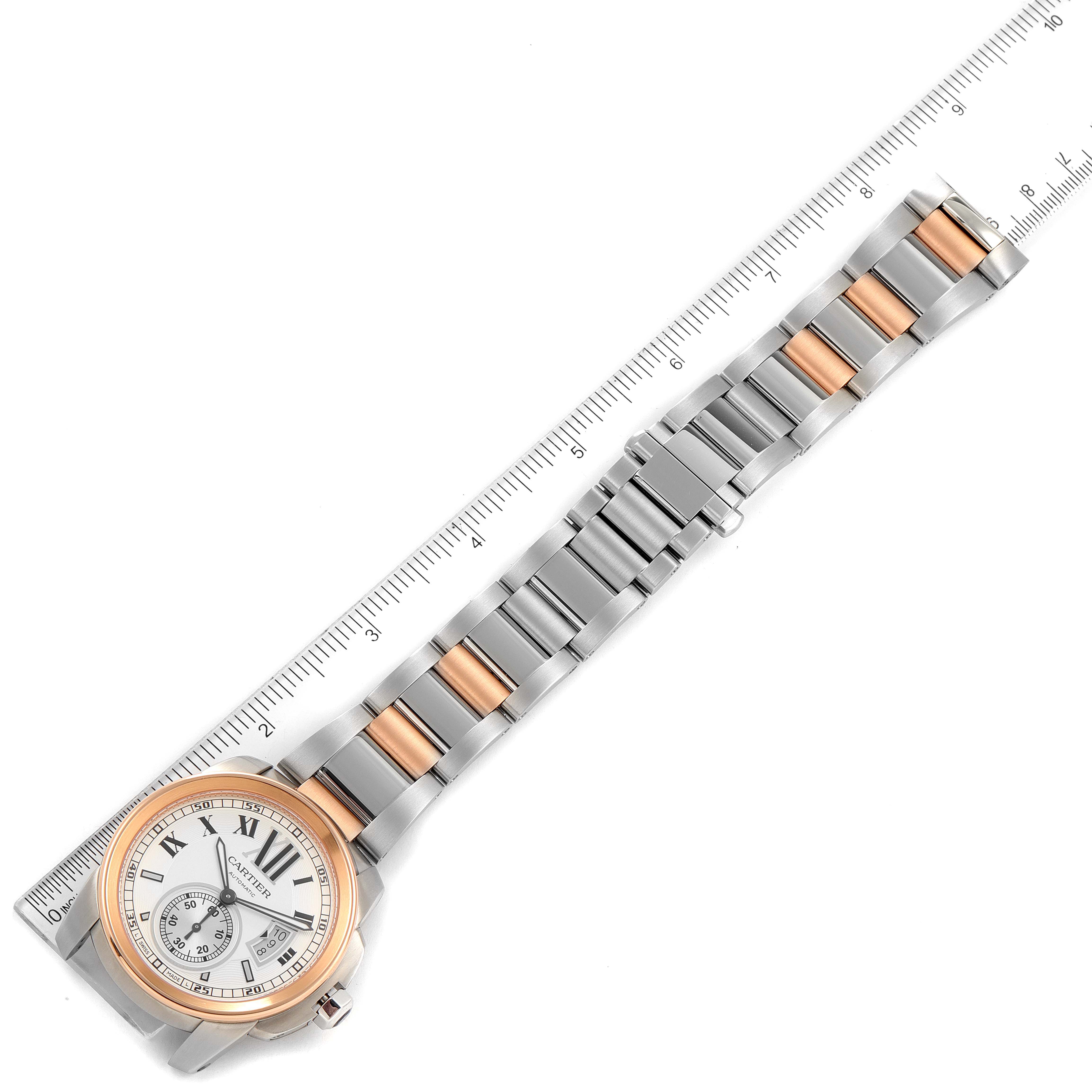 The image shows the full length of a Calibre de Cartier watch by Cartier, including the face, bezel, and metal bracelet alongside a ruler.