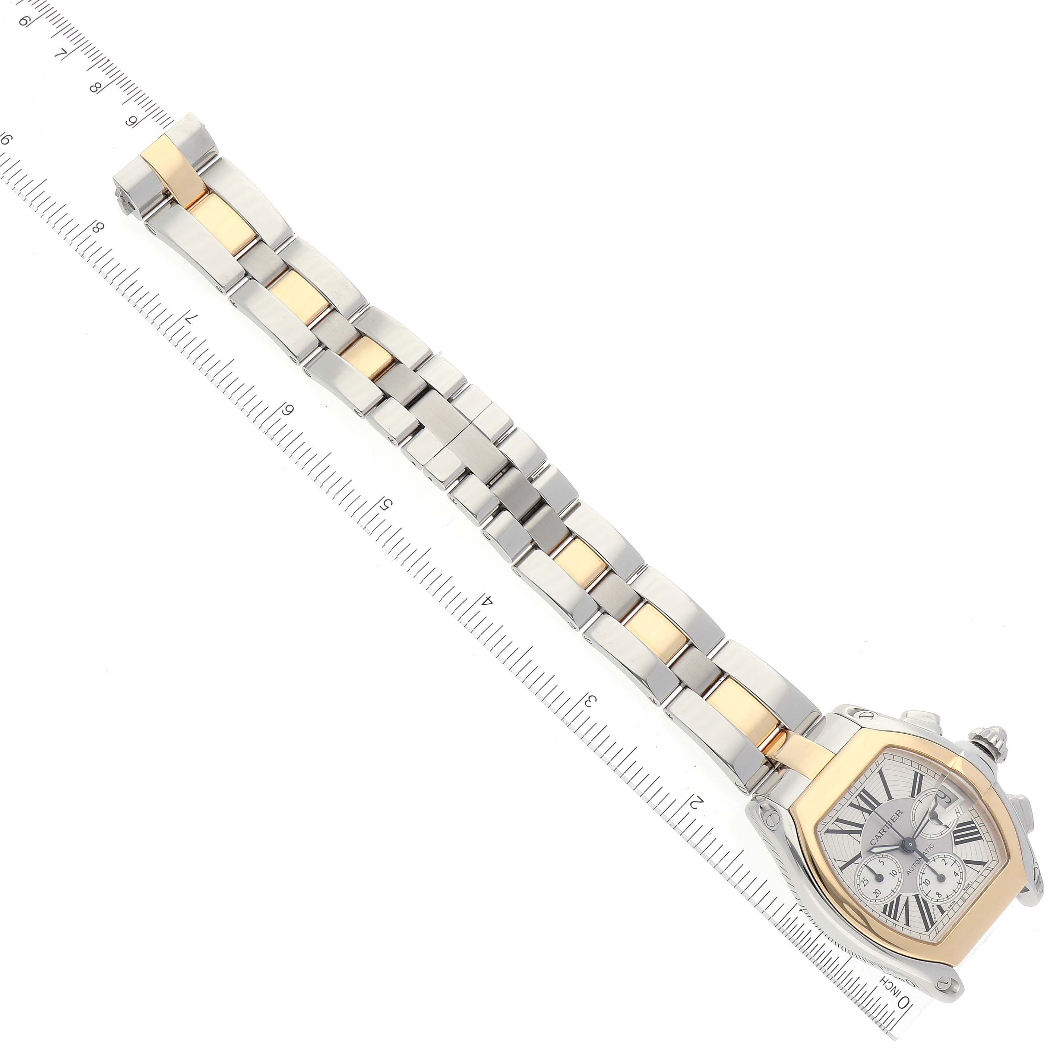 This image shows the Cartier Roadster W62027Z1 Men's Steel and Gold (two tone) Silver Dial W62027Z1 Men's Steel and Gold (two tone) Silver Dial watch from a top-down angle, featuring the face, bezel, and full bracelet against a ruler.