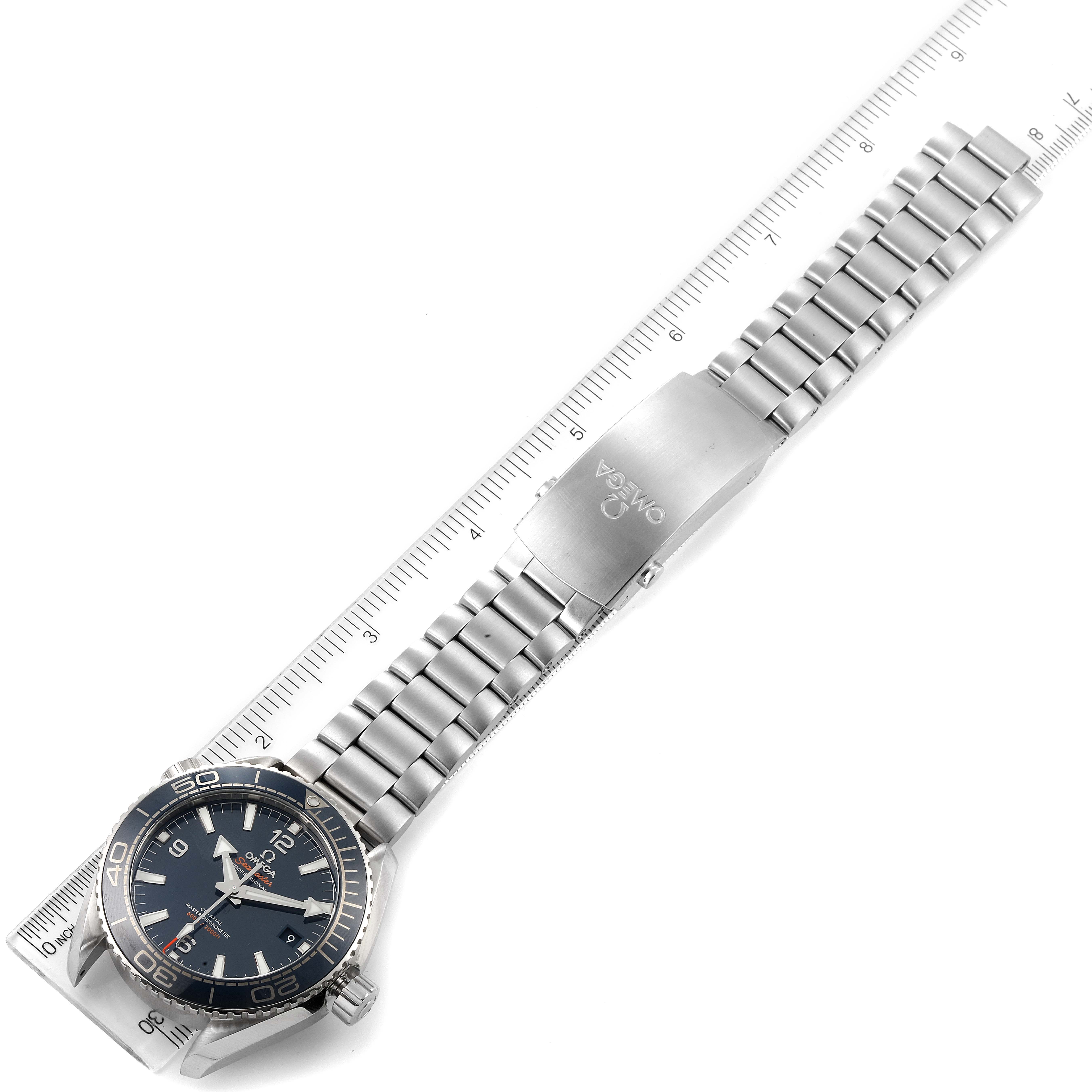 The Planet Ocean model by Omega is shown laid flat with its stainless steel bracelet extended and aligned with a ruler.