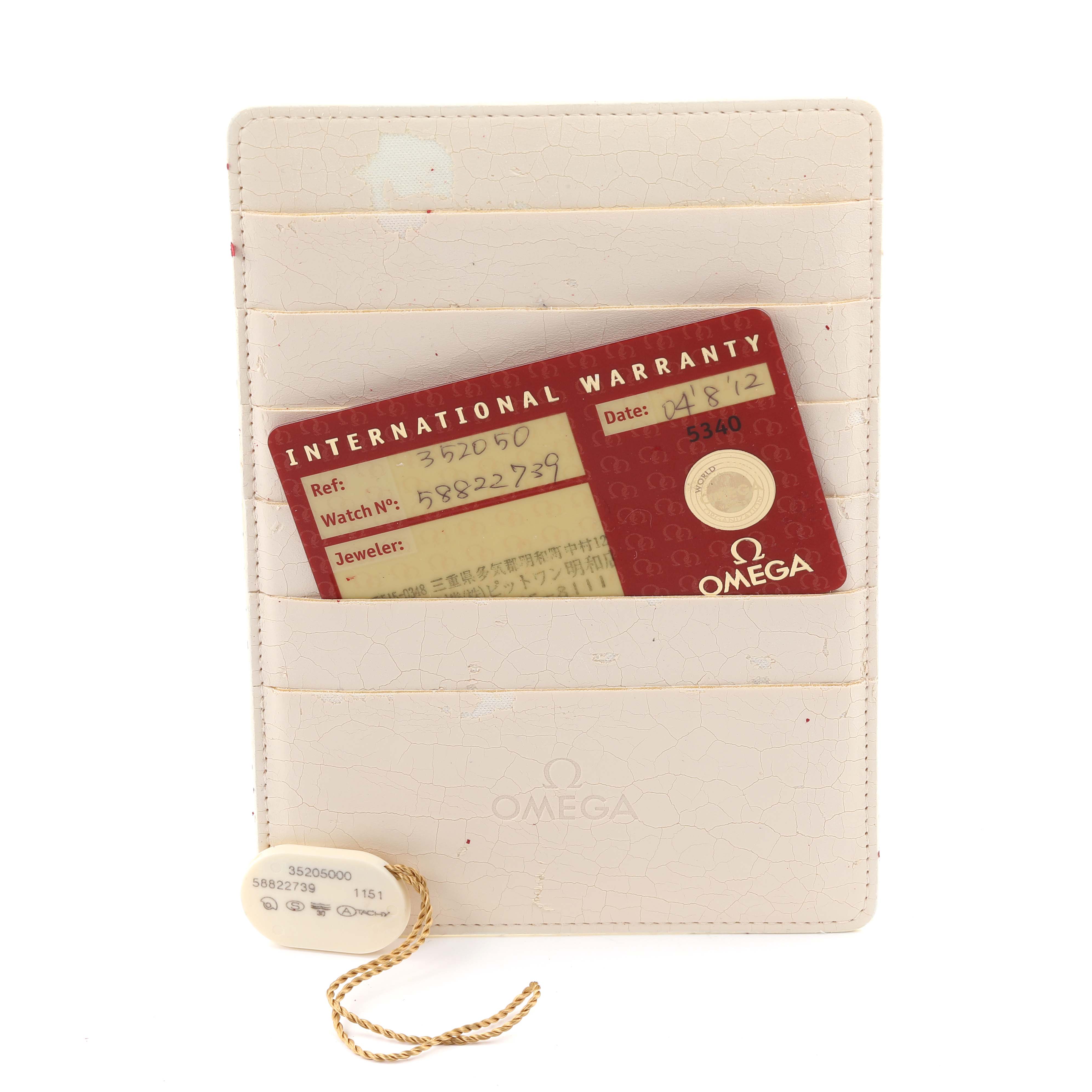 The image shows an Omega Speedmaster 3520.50.00 Men
s Stainless Steel Black Dial 3520.50.00 Men
s Stainless Steel Black Dial warranty card and a tag, both resting on a white holder.