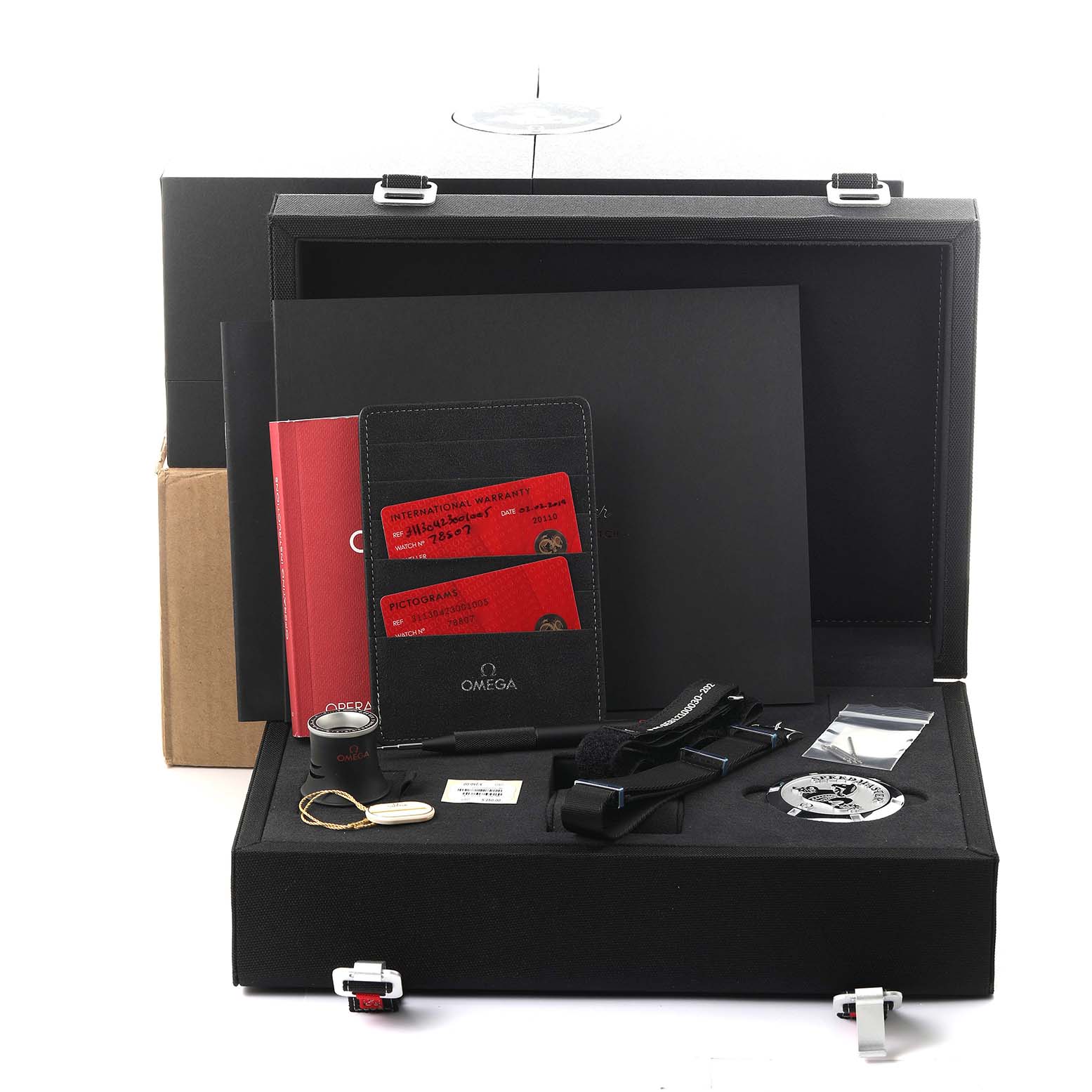 The Omega Speedmaster 311.30.42.30.01.005 Men's Stainless Steel Black Dial 311.30.42.30.01.005 Men's Stainless Steel Black Dial package is shown, featuring documentation, strap, tool, and medallion from a top-down angle.