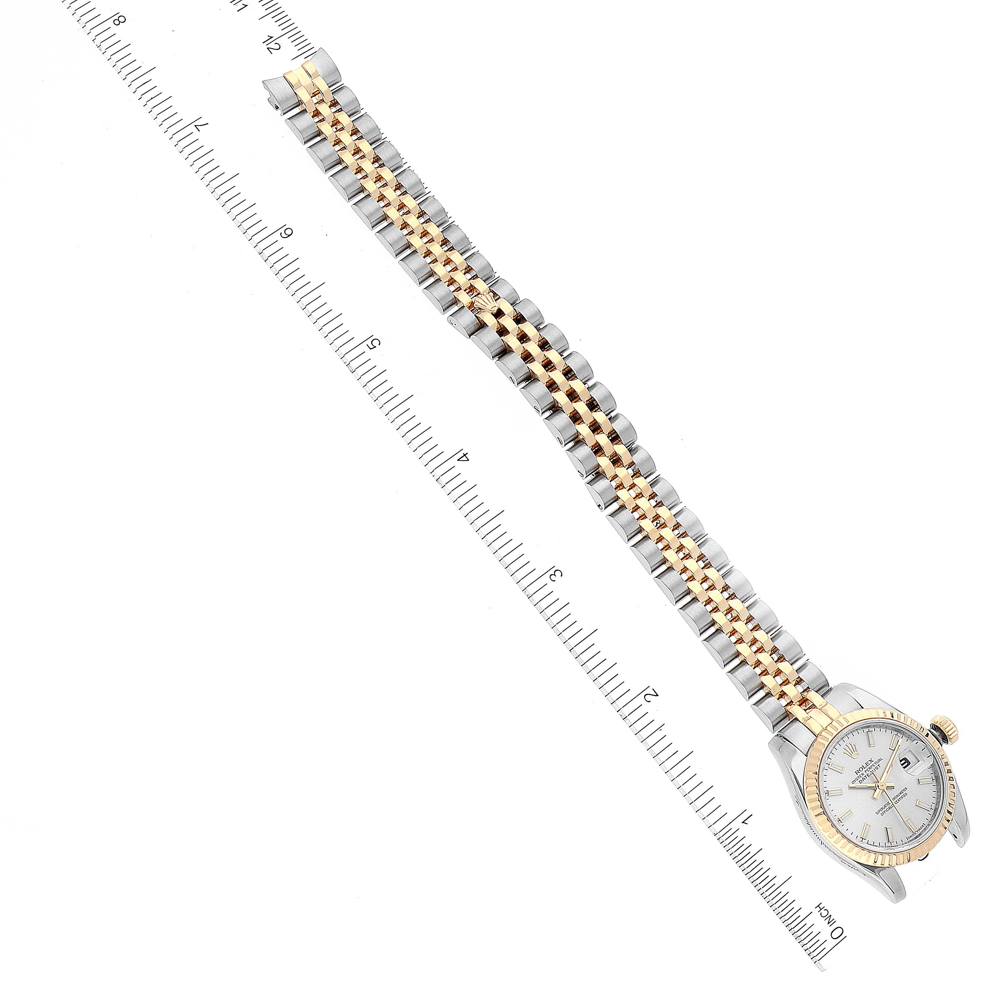 This image shows a top-view angle of a Rolex Datejust 179173 Women's Steel and Gold (two tone) Silver Dial 179173 Women's Steel and Gold (two tone) Silver Dial watch, showcasing its face and two-tone bracelet along with a ruler for scale.