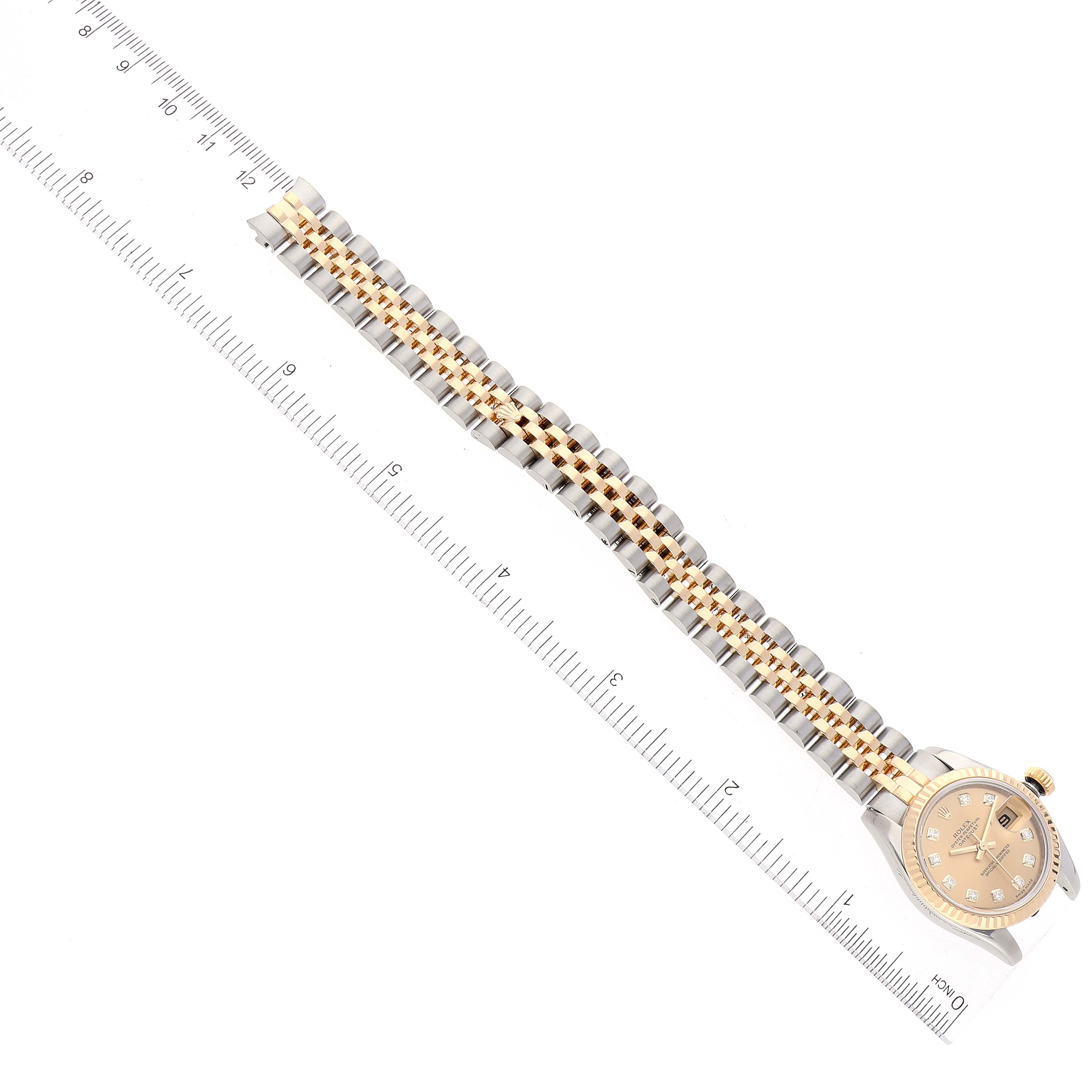 The image shows a rolled-out Rolex Datejust 179173 Women's Steel and Gold (two tone) Champagne Dial 179173 Women's Steel and Gold (two tone) Champagne Dial watch, highlighting its bracelet with an integrated ruler for scale.