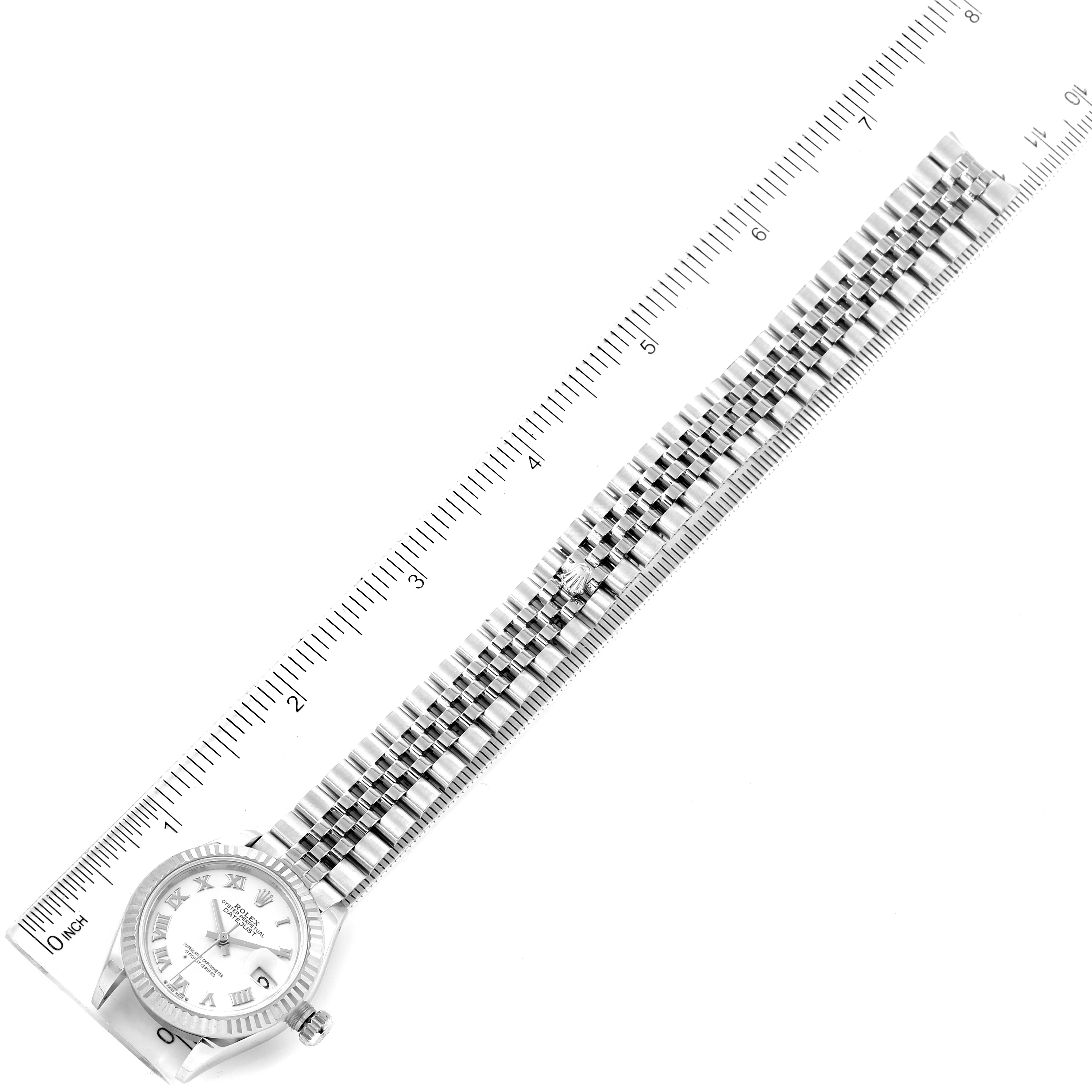 The image shows a Rolex Datejust 279174 Women
s Stainless Steel White Dial 279174 Women
s Stainless Steel White Dial watch laid flat with its face and bracelet aligned beside a ruler for measurement.