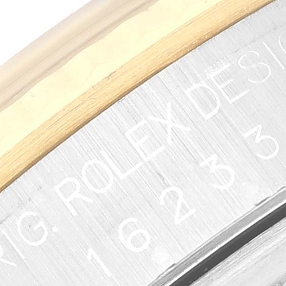 This close-up image of a Rolex Datejust 16233 Men's Steel and Gold (two tone) Grey Dial 16233 Men's Steel and Gold (two tone) Grey Dial watch displays part of the bezel and engraved text on its case.