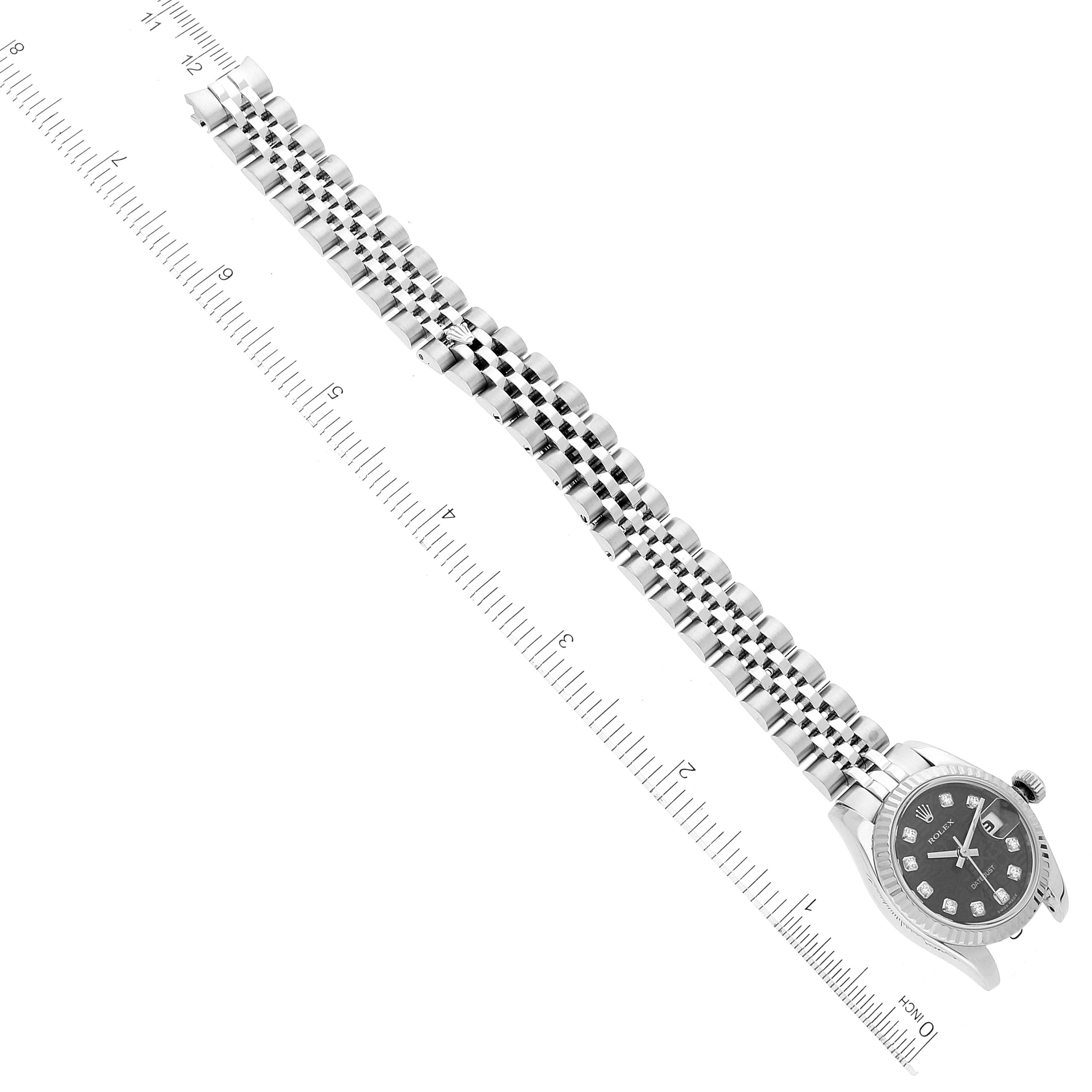 The Rolex Datejust 179174 Women's Stainless Steel Black Dial 179174 Women's Stainless Steel Black Dial watch is shown from a diagonal top-down angle, displaying the face and bracelet alongside a ruler for scale.