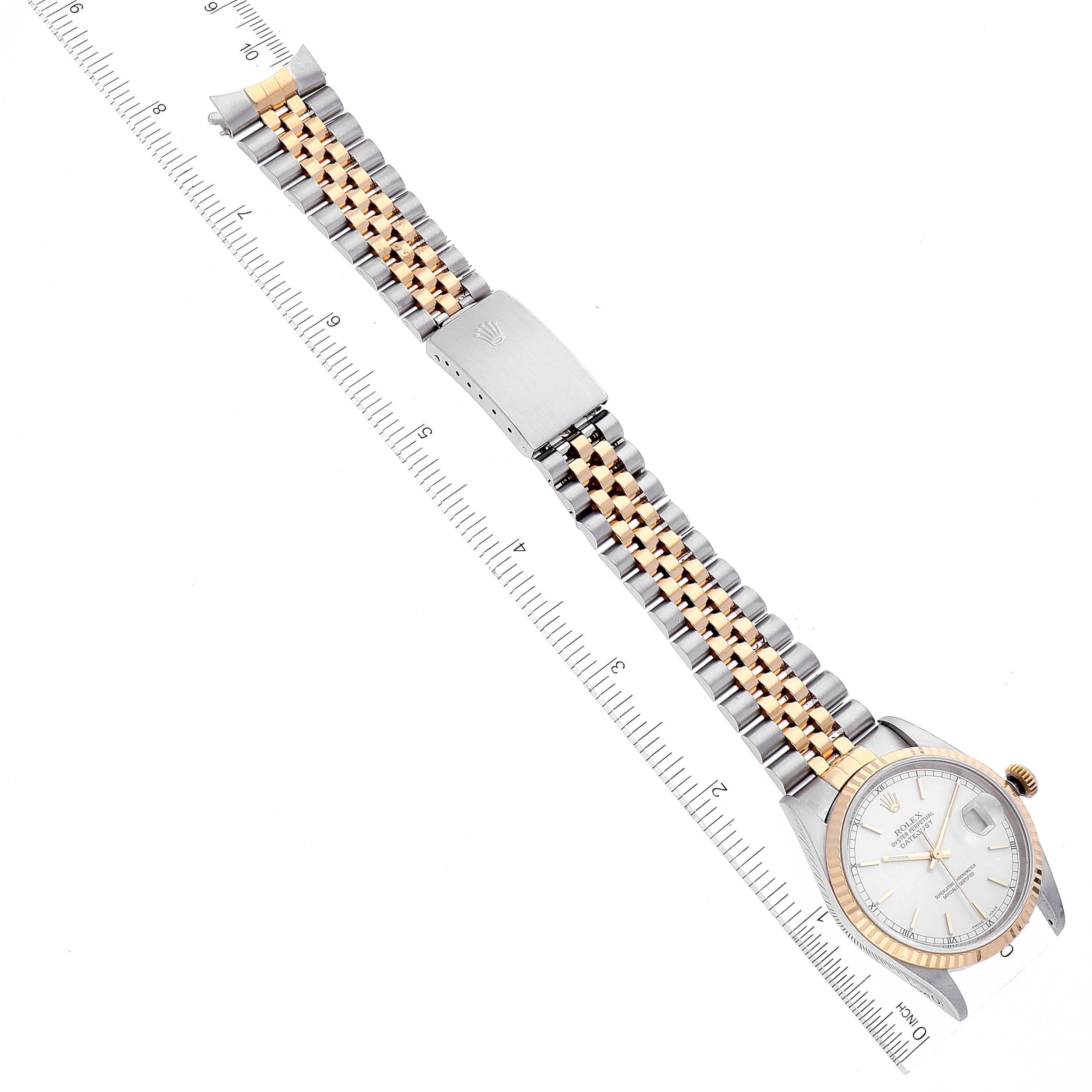 The Rolex Datejust 16233 Men's Steel and Gold (two tone) Silver Dial 16233 Men's Steel and Gold (two tone) Silver Dial watch is shown flat, displaying the face, bracelet, and clasp alongside a ruler for measurement.