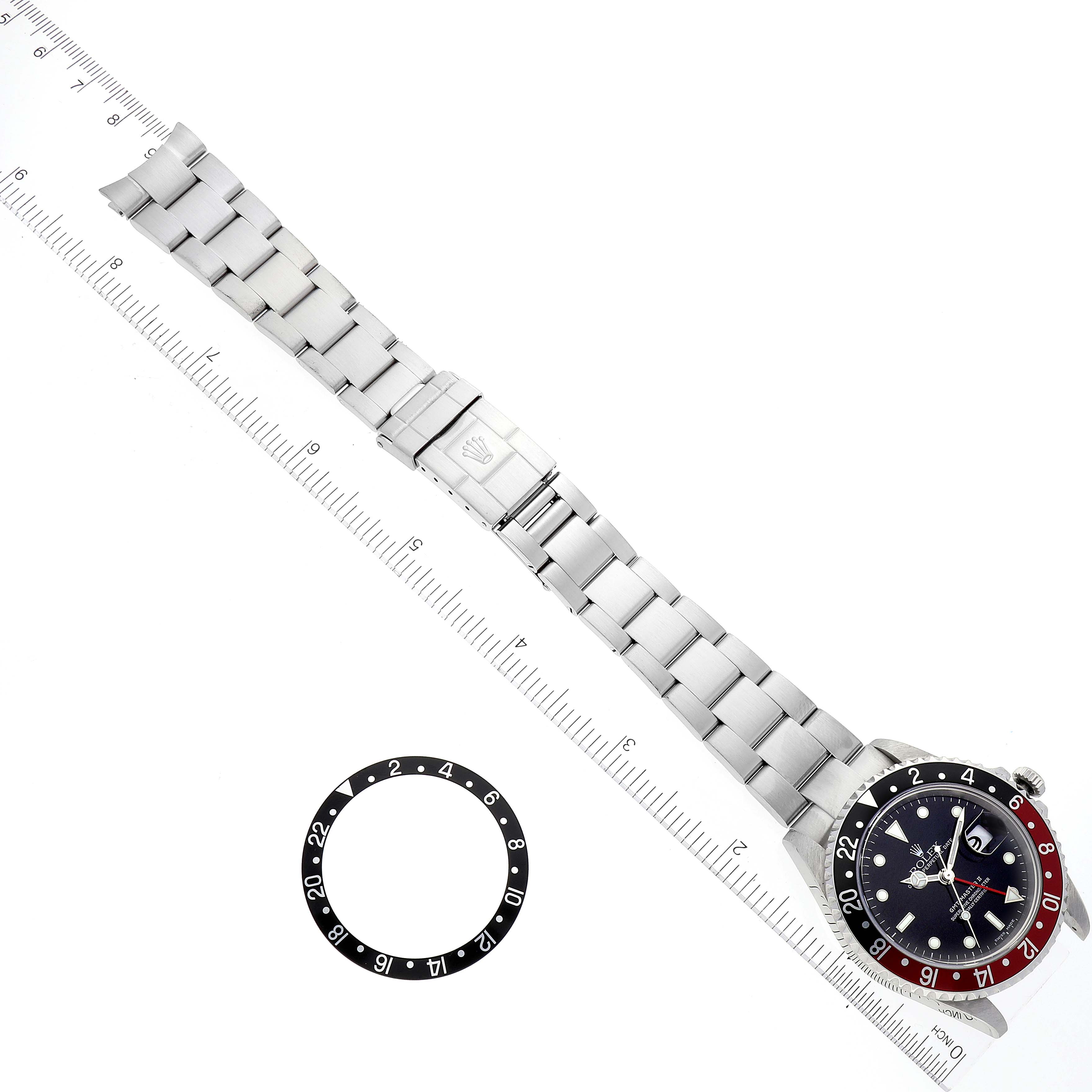 The image shows the full length of a Rolex GMT-Master 16710 Men
s Stainless Steel Black Dial 16710 Men
s Stainless Steel Black Dial watch and a bezel insert, placed next to a ruler for scale.