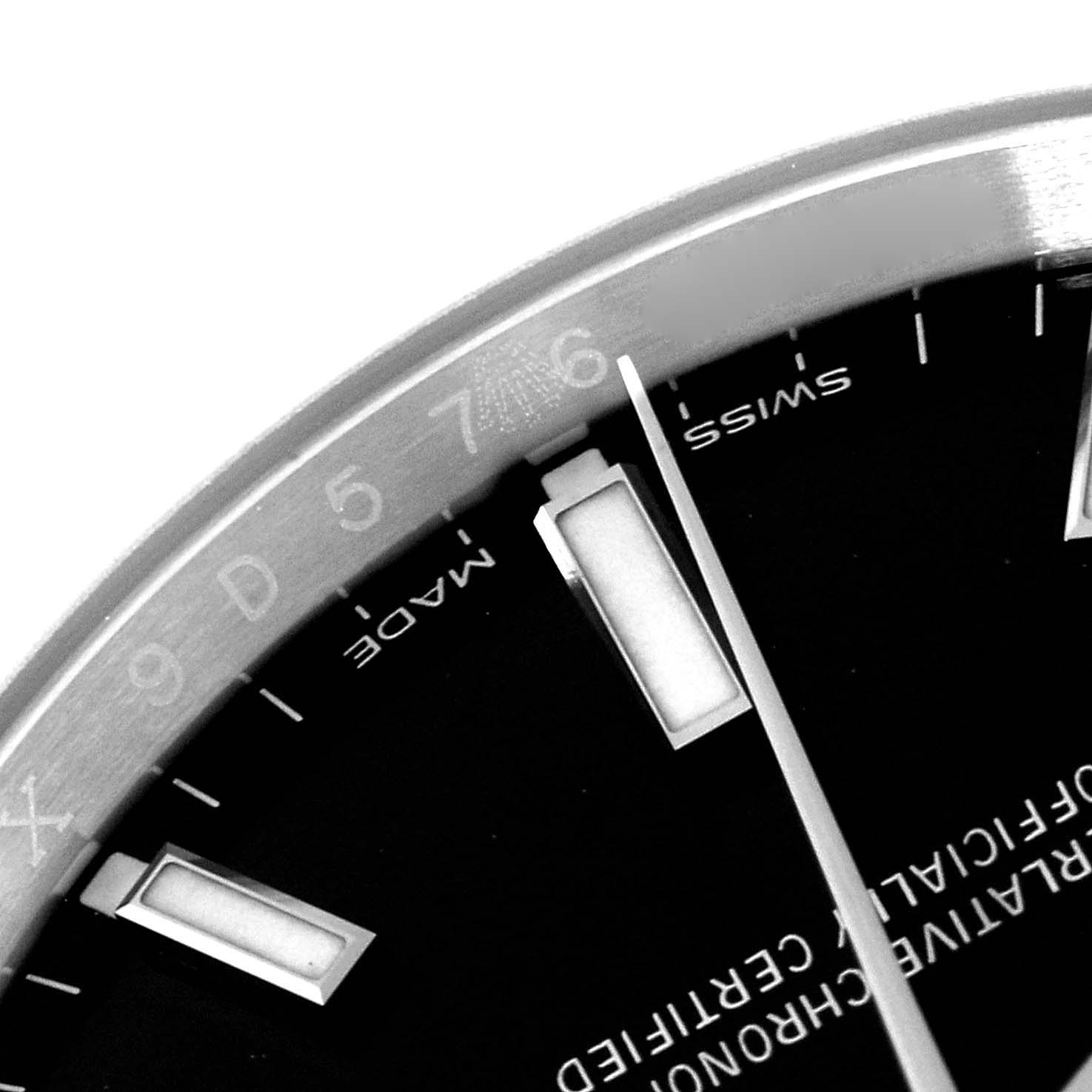 This close-up image shows the upper right portion of the dial and bezel of a Rolex Oyster Perpetual 114200 Men's Stainless Steel Black Dial 114200 Men's Stainless Steel Black Dial watch, including hour markers and partial branding text.