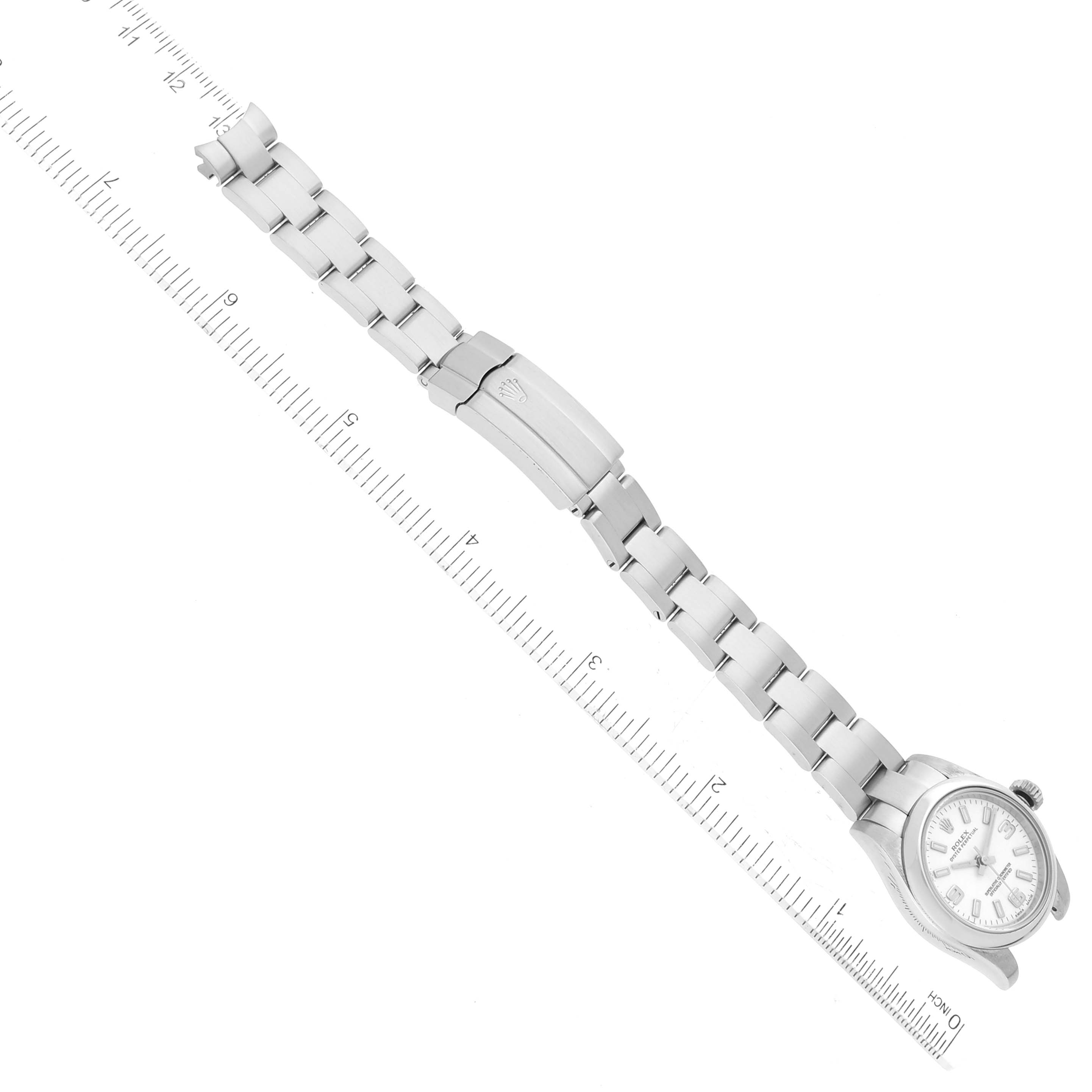 This image shows a top-down view of a Rolex Oyster Perpetual 176200 Women's Stainless Steel White Dial 176200 Women's Stainless Steel White Dial watch, displaying its face, bracelet, and clasp against a ruler for scale.
