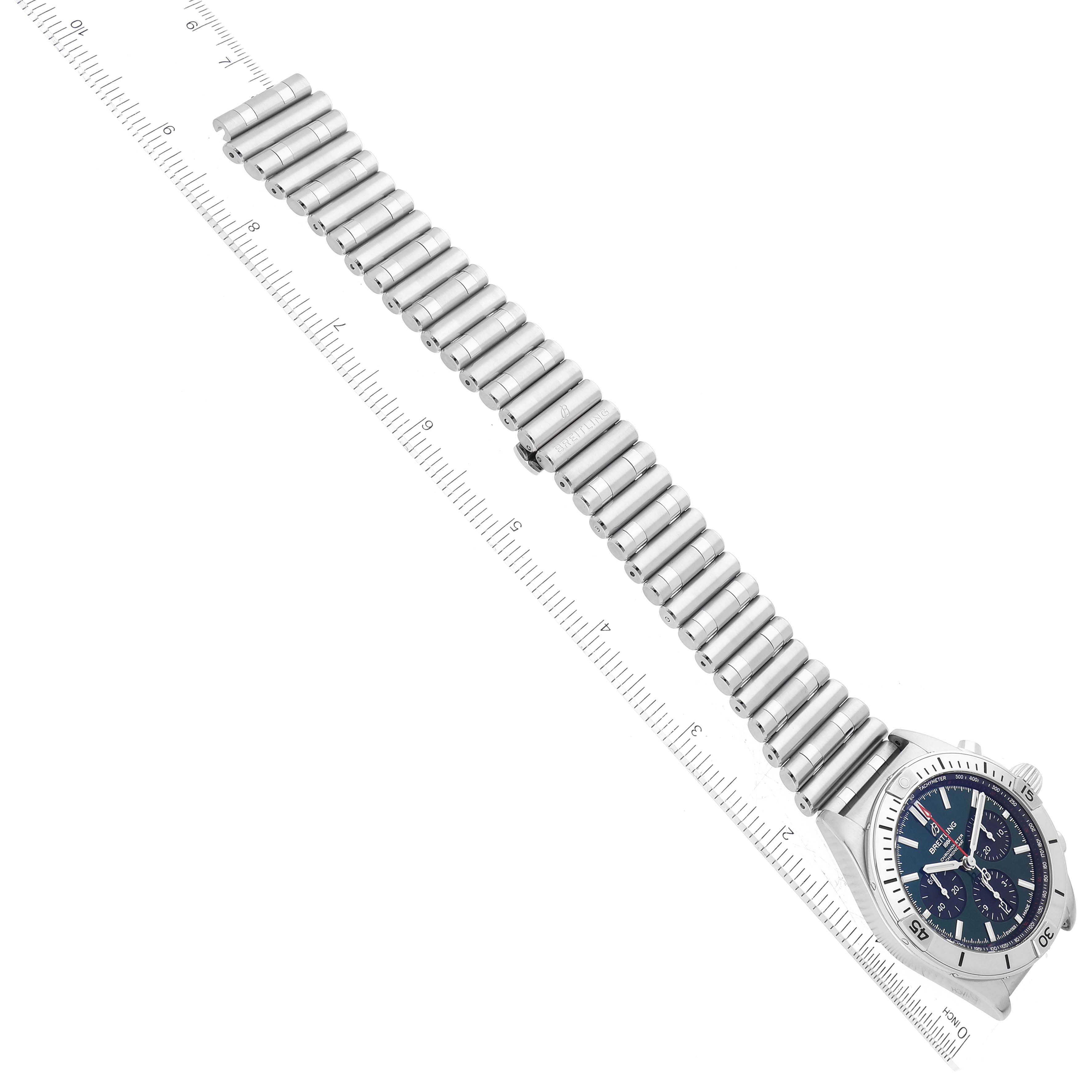 The Breitling Chronomat AB0134 Men
s Stainless Steel Green Dial AB0134 Men
s Stainless Steel Green Dial watch is shown diagonally with a focus on its face and stainless steel bracelet alongside a ruler.