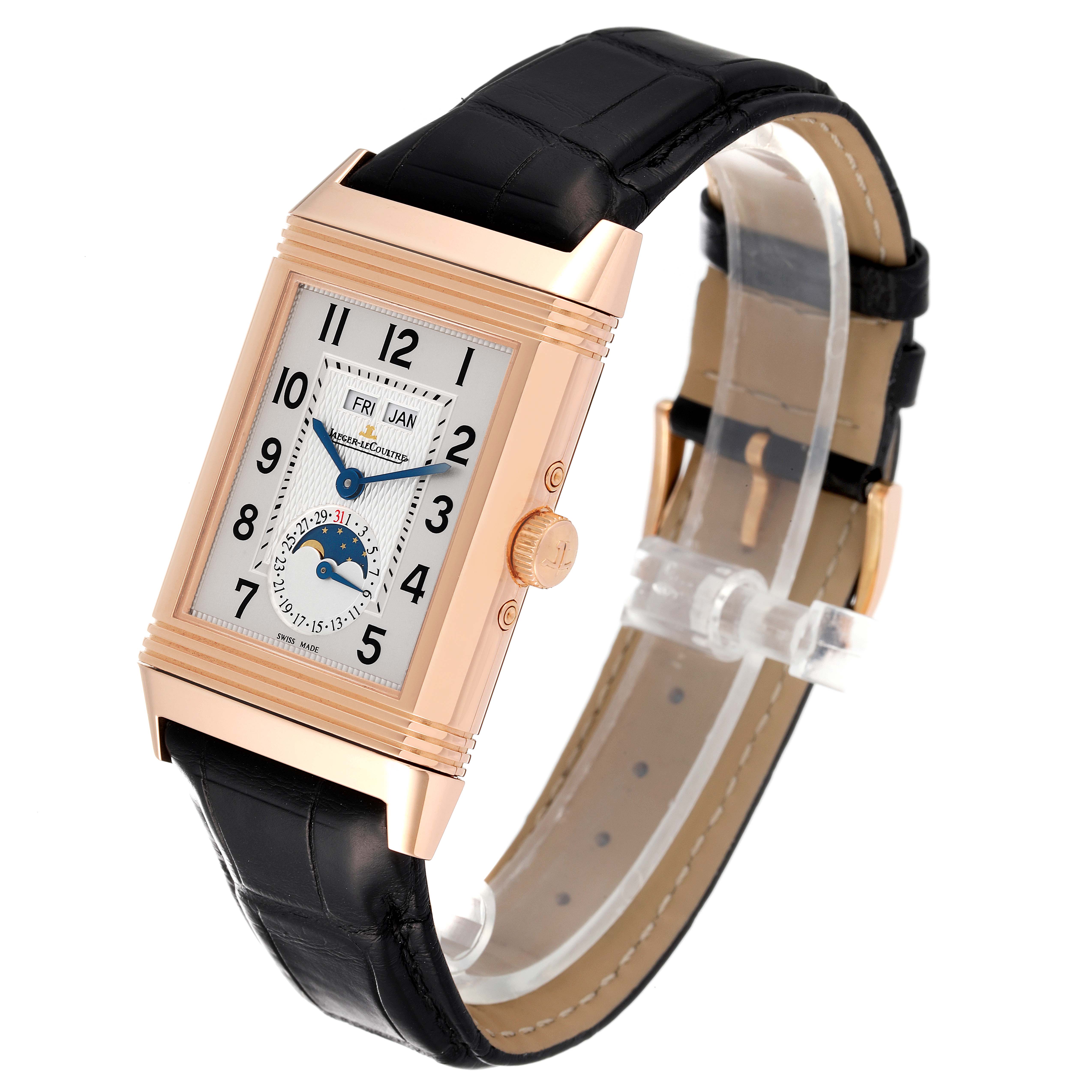 The image showcases a Jaeger LeCoultre Reverso Q3752520 Men's Rose Gold Silver Dial Q3752520 Men's Rose Gold Silver Dial watch from a three-quarter angle, revealing its black strap, rectangular case, and visible dial with complications.