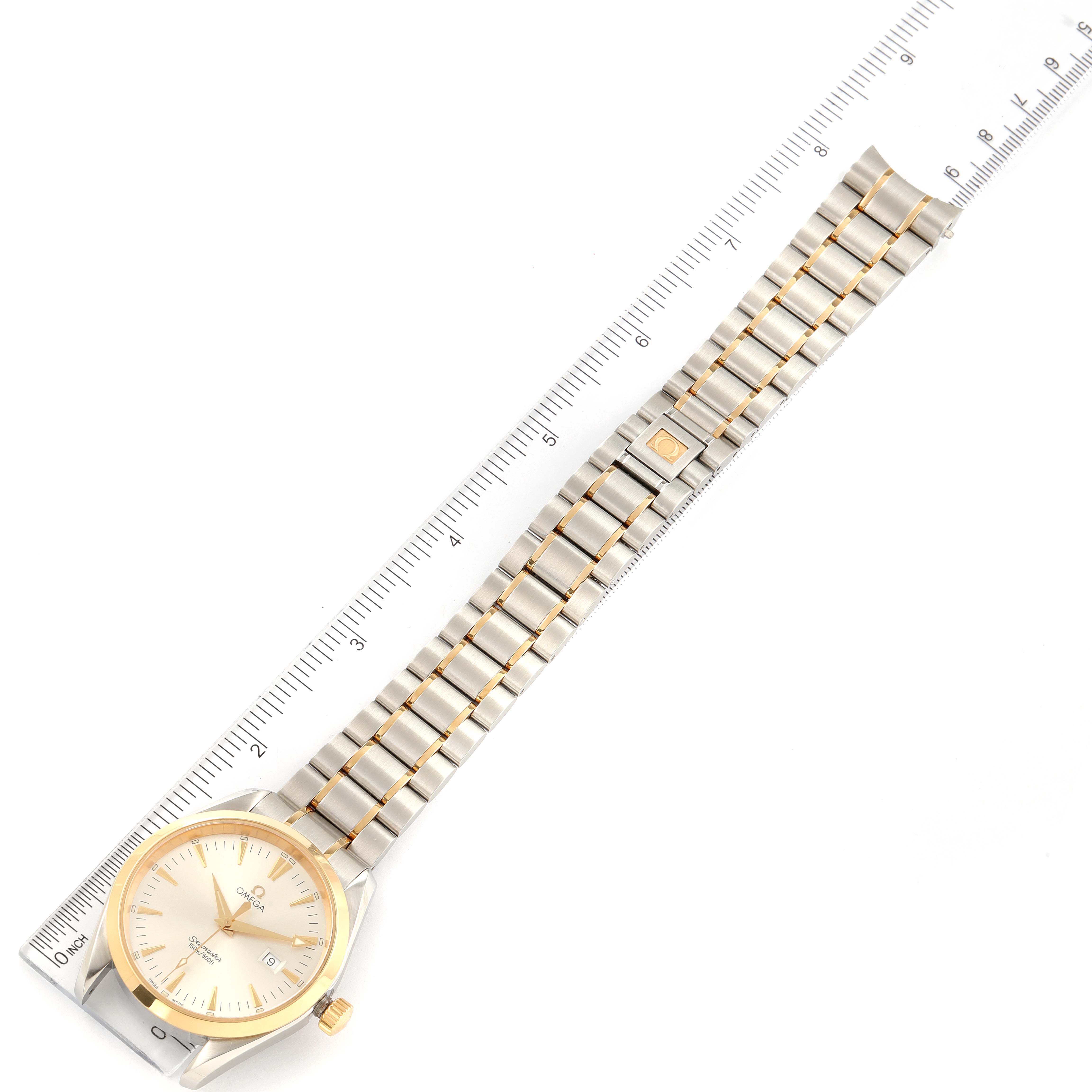 The image shows an Omega Aqua Terra 2317.30.00 Men's Steel and Gold (two tone) Silver Dial 2317.30.00 Men's Steel and Gold (two tone) Silver Dial watch with a ruler for scale, displaying the entire band and face from an overhead angle.