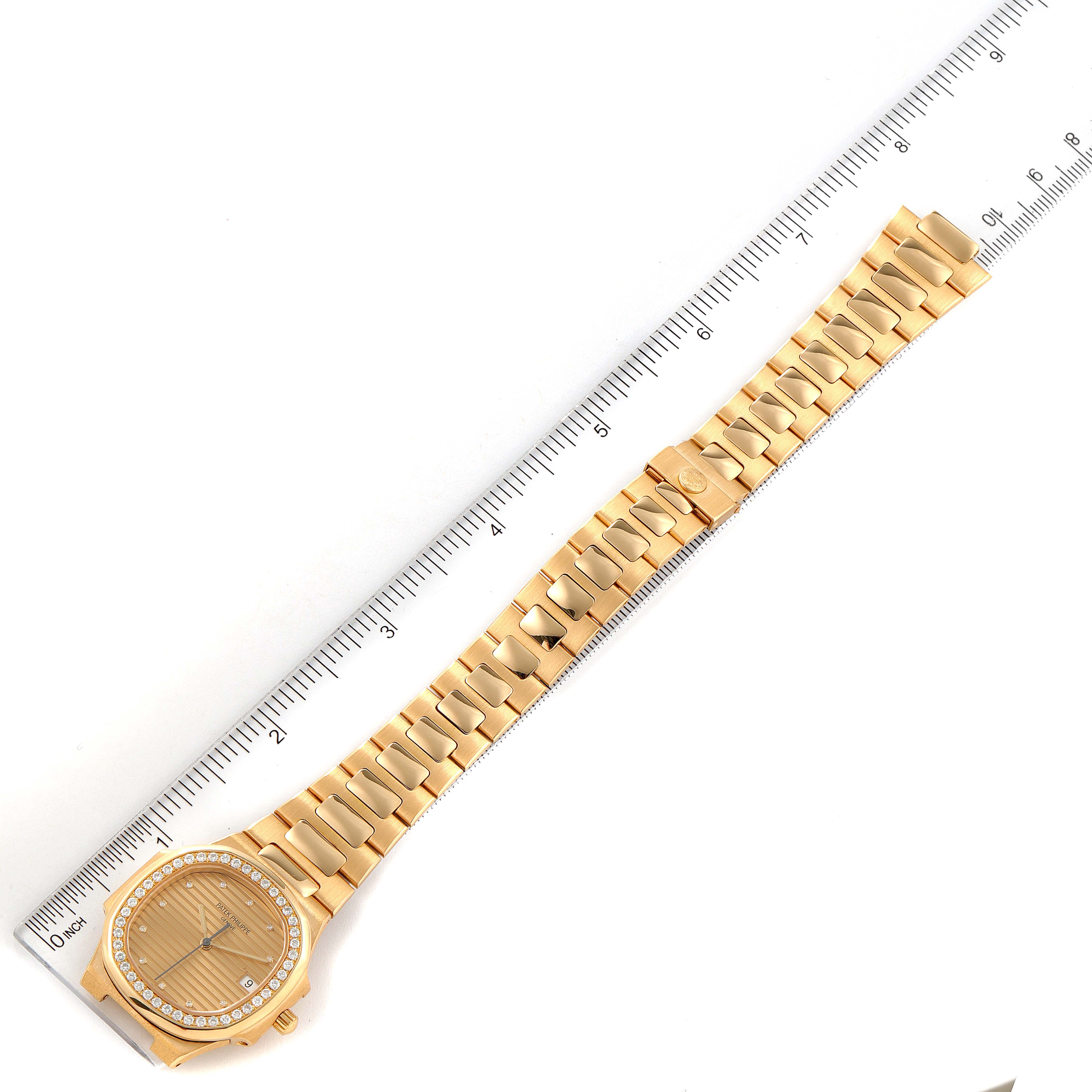 The image shows a gold Patek Philippe Nautilus 3900/003 Women's Yellow Gold Champagne Dial 3900/003 Women's Yellow Gold Champagne Dial watch, displayed flat and fully extended, next to a ruler for scale.