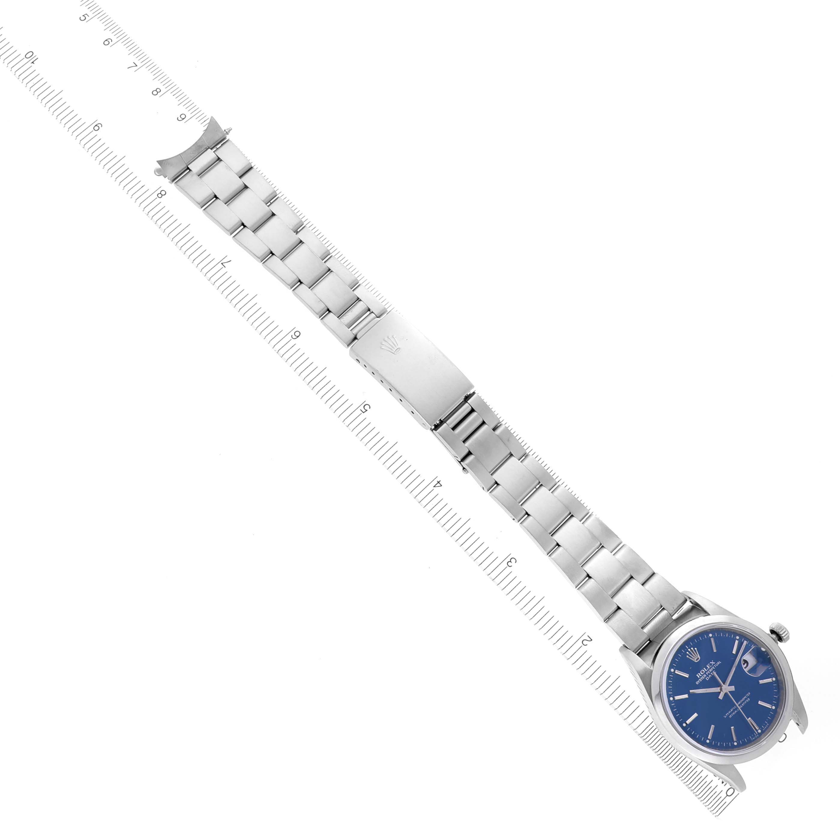 The Rolex Date 15200 Men's Stainless Steel Blue Dial 15200 Men's Stainless Steel Blue Dial watch is shown from a top-down angle, displaying the face, bracelet, and clasp in full along with a ruler for scale.