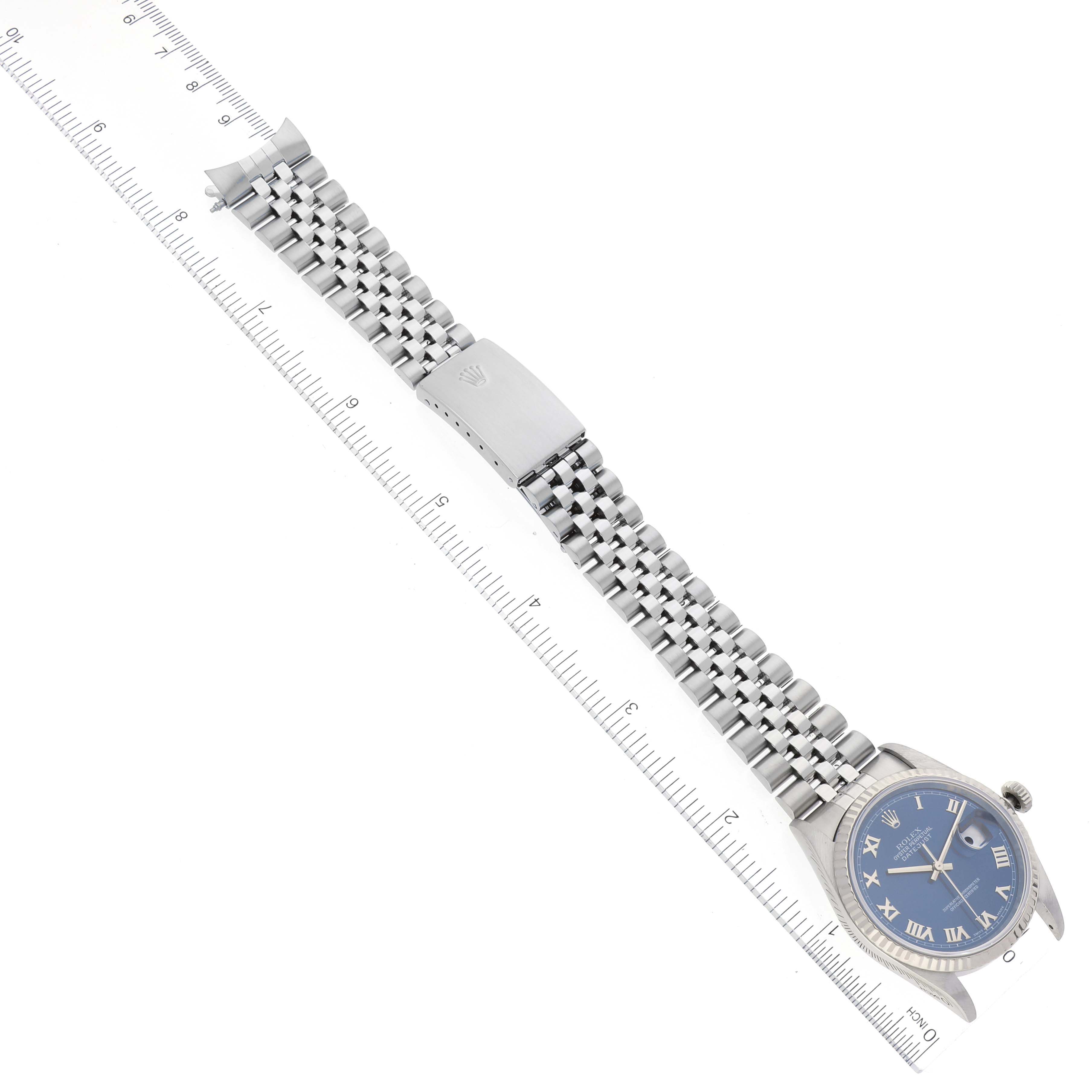 The image shows the Rolex Datejust 16234 Men's Stainless Steel Blue Dial 16234 Men's Stainless Steel Blue Dial watch flat, displaying its face, bracelet, and clasp, aligned next to a ruler for scale.