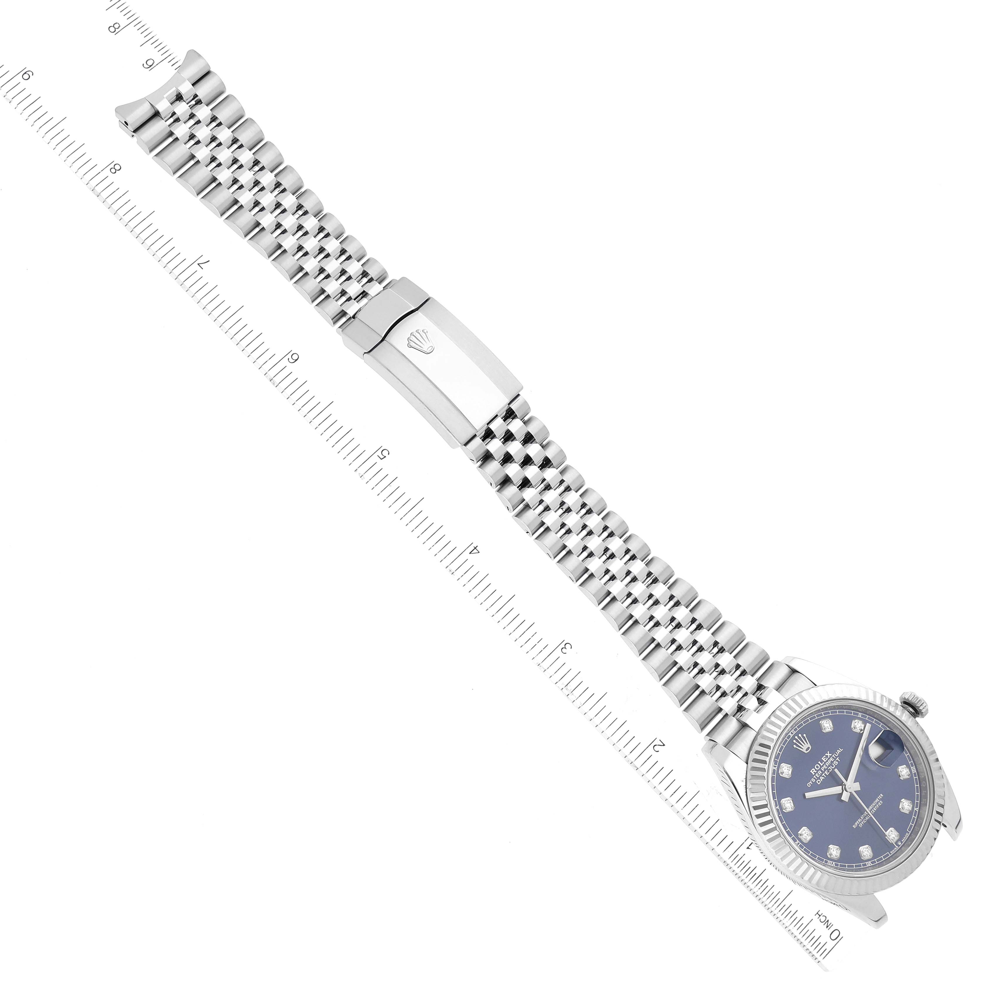 The Rolex Datejust 41 126334 Men
s Stainless Steel Blue Dial 126334 Men
s Stainless Steel Blue Dial watch is shown in a top-down angle, displaying the face, bracelet, and clasp alongside a measuring ruler.