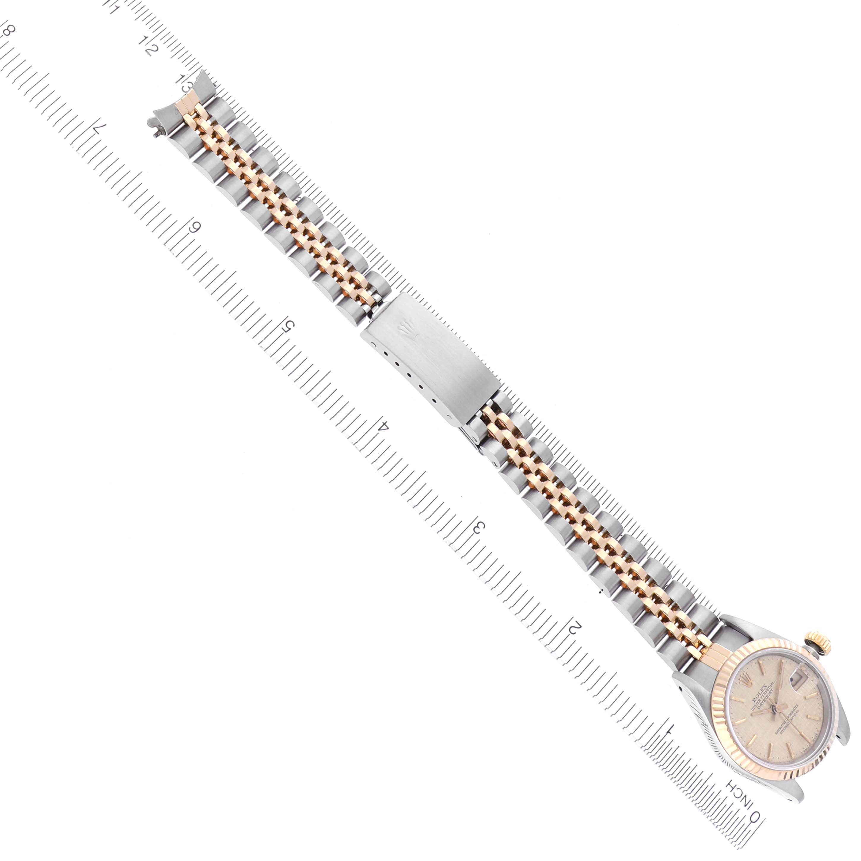 The image shows a top-down view of a Rolex Datejust 69173 Women's Steel and Gold (two tone) Champagne Dial 69173 Women's Steel and Gold (two tone) Champagne Dial watch with its full bracelet next to a ruler.