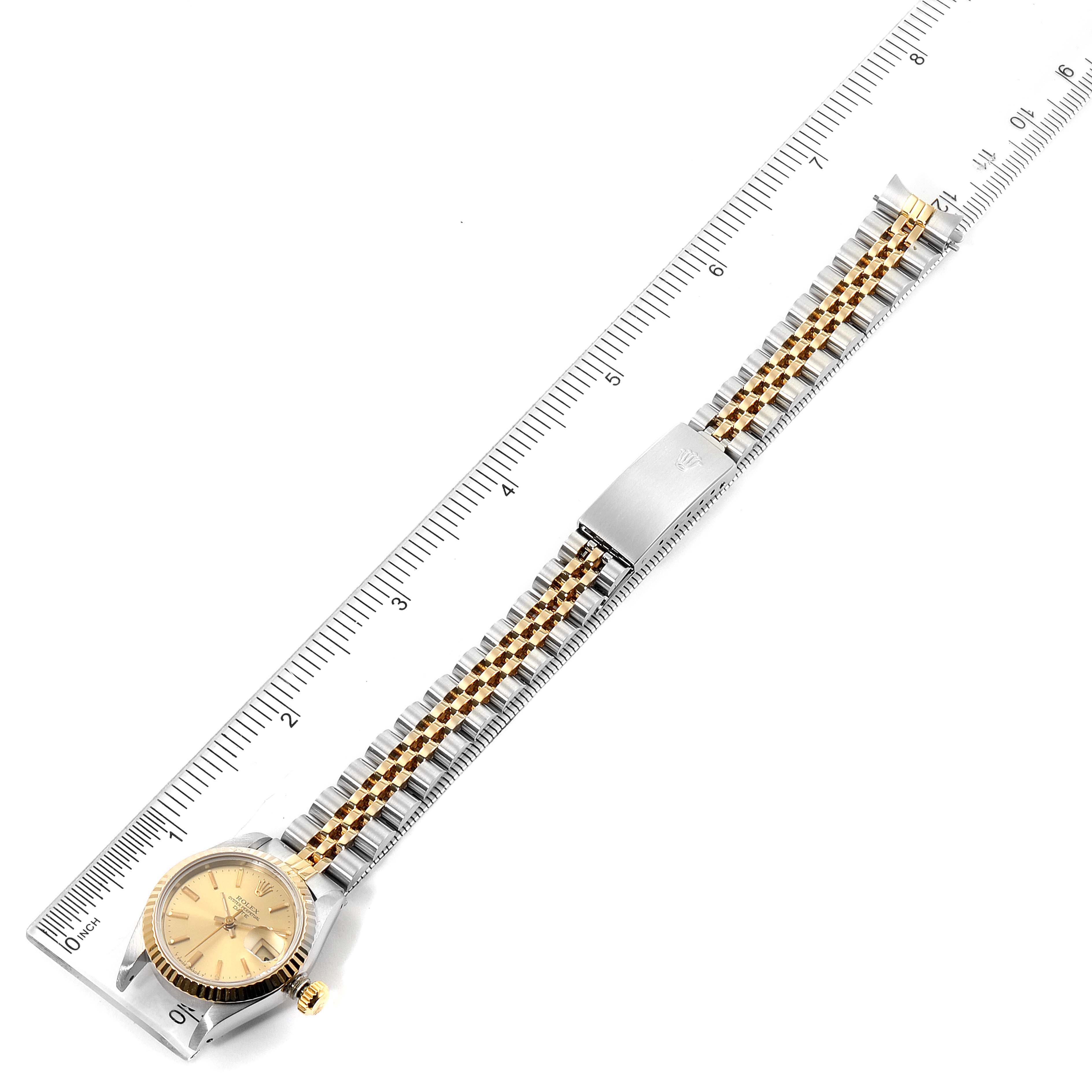 This image shows a Rolex Datejust 69173 Women's Steel and Gold (two tone) Champagne Dial 69173 Women's Steel and Gold (two tone) Champagne Dial watch placed on a ruler, featuring the face, bezel, and full bracelet with a clasp.