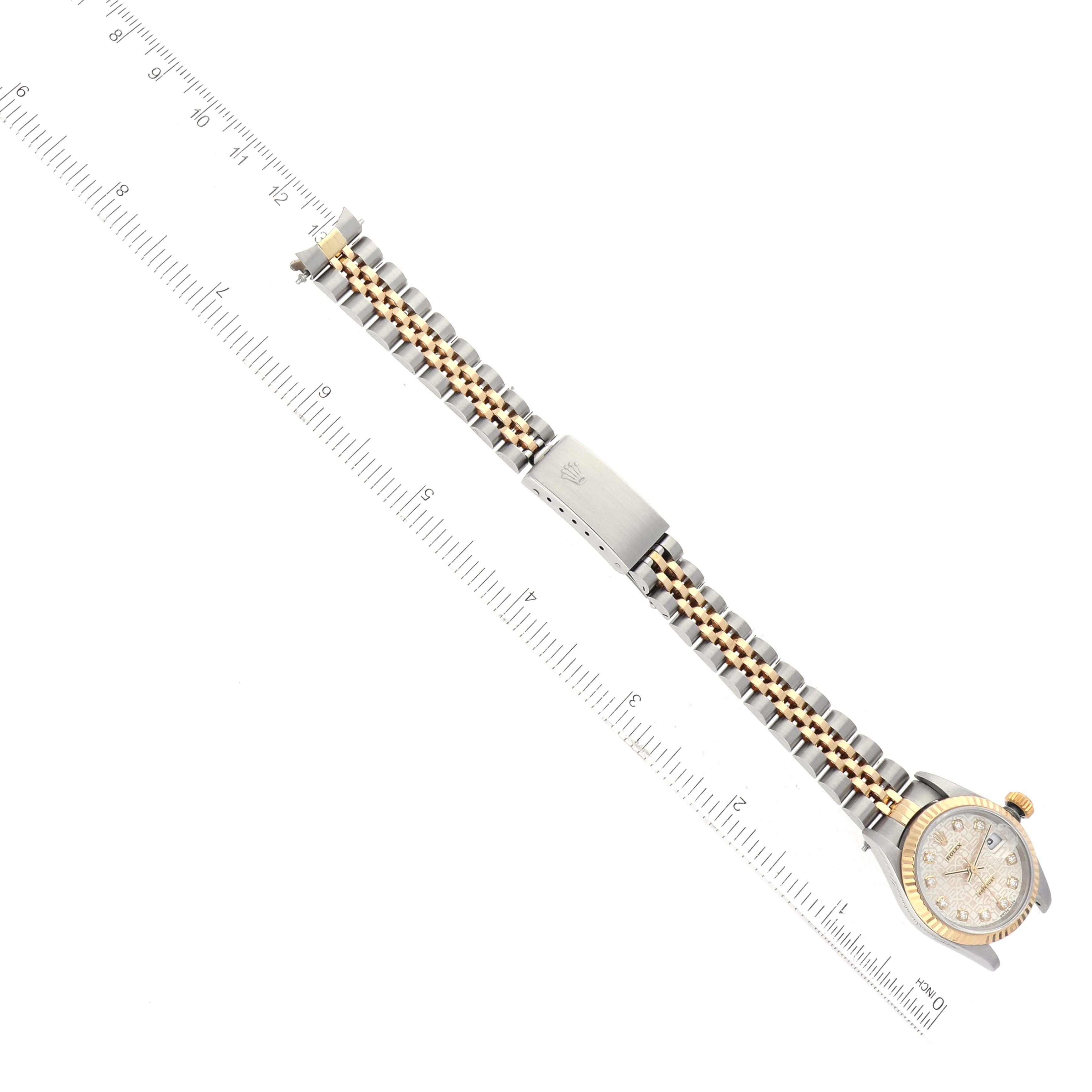 The image shows a Rolex Datejust 79173 Women's Steel and Gold (two tone) Silver Dial 79173 Women's Steel and Gold (two tone) Silver Dial watch diagonally, featuring its face, bracelet, and clasp alongside a ruler for scale.