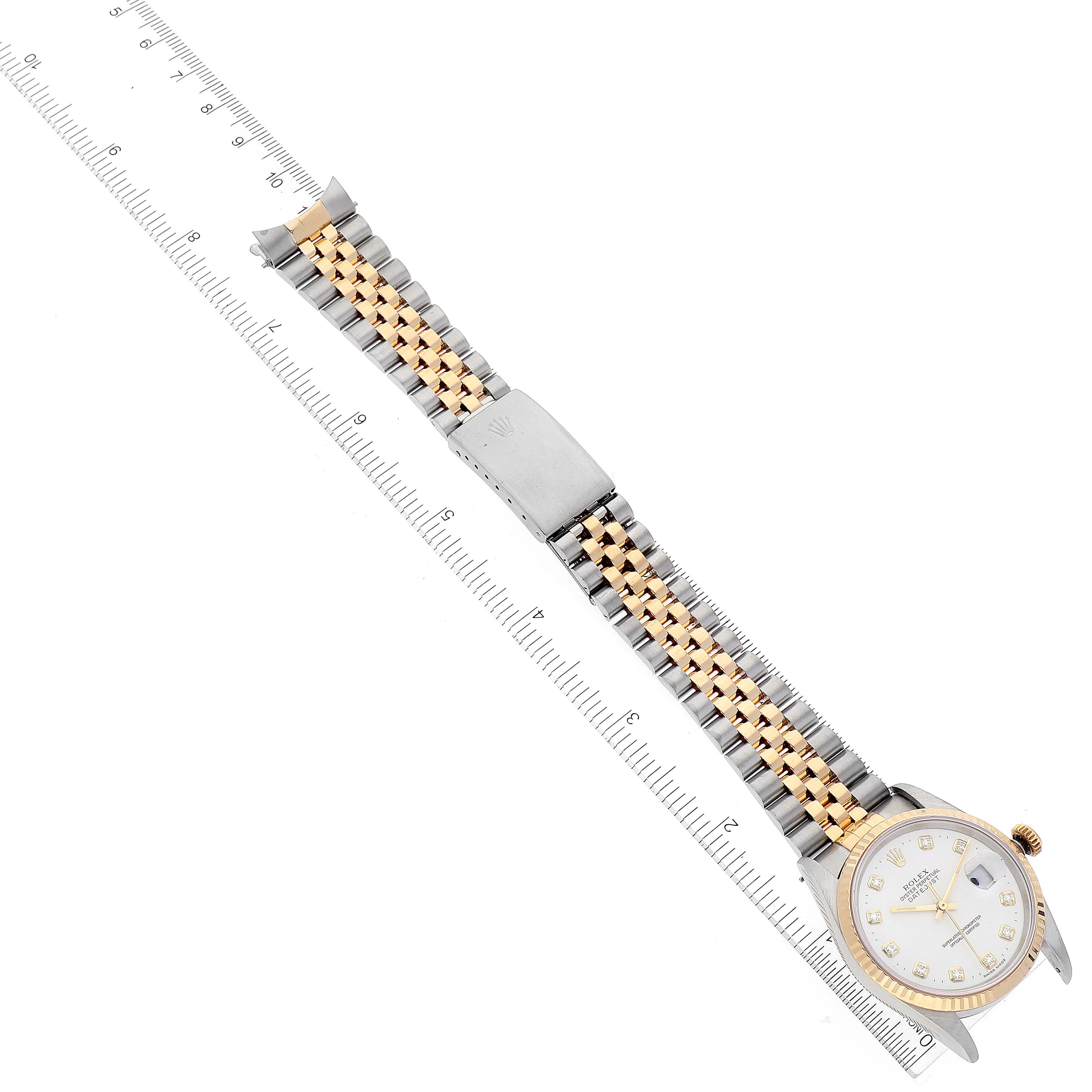 This top-down view of the Rolex Datejust 16233 Men's Steel and Gold (two tone) White Dial 16233 Men's Steel and Gold (two tone) White Dial watch displays the entire watch, including the face, bezel, and two-tone bracelet, aligned with a ruler.