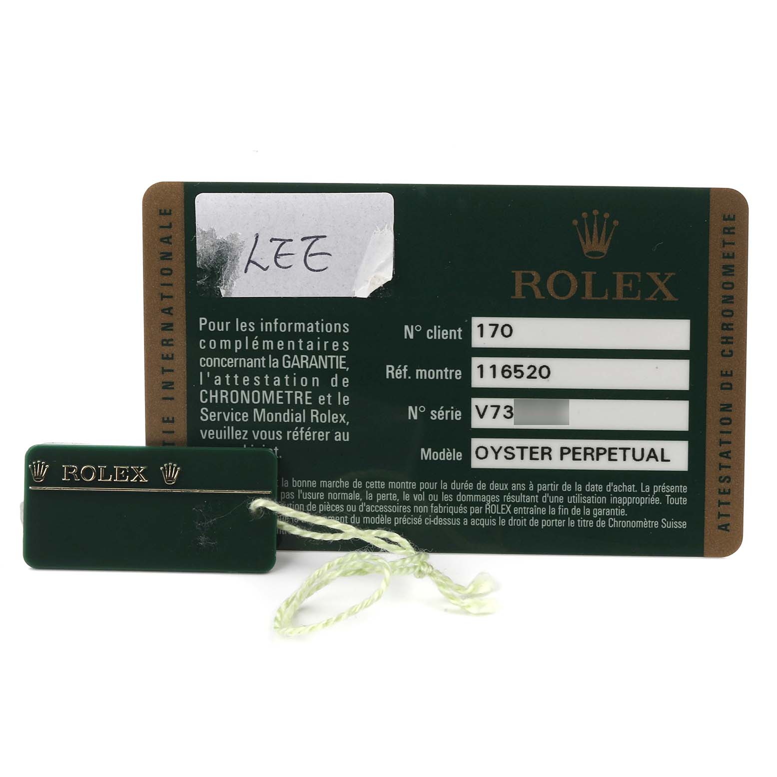 The image shows a Rolex Daytona 116520 Men's Stainless Steel White Dial 116520 Men's Stainless Steel White Dial warranty card and a green tag with the brand logo.