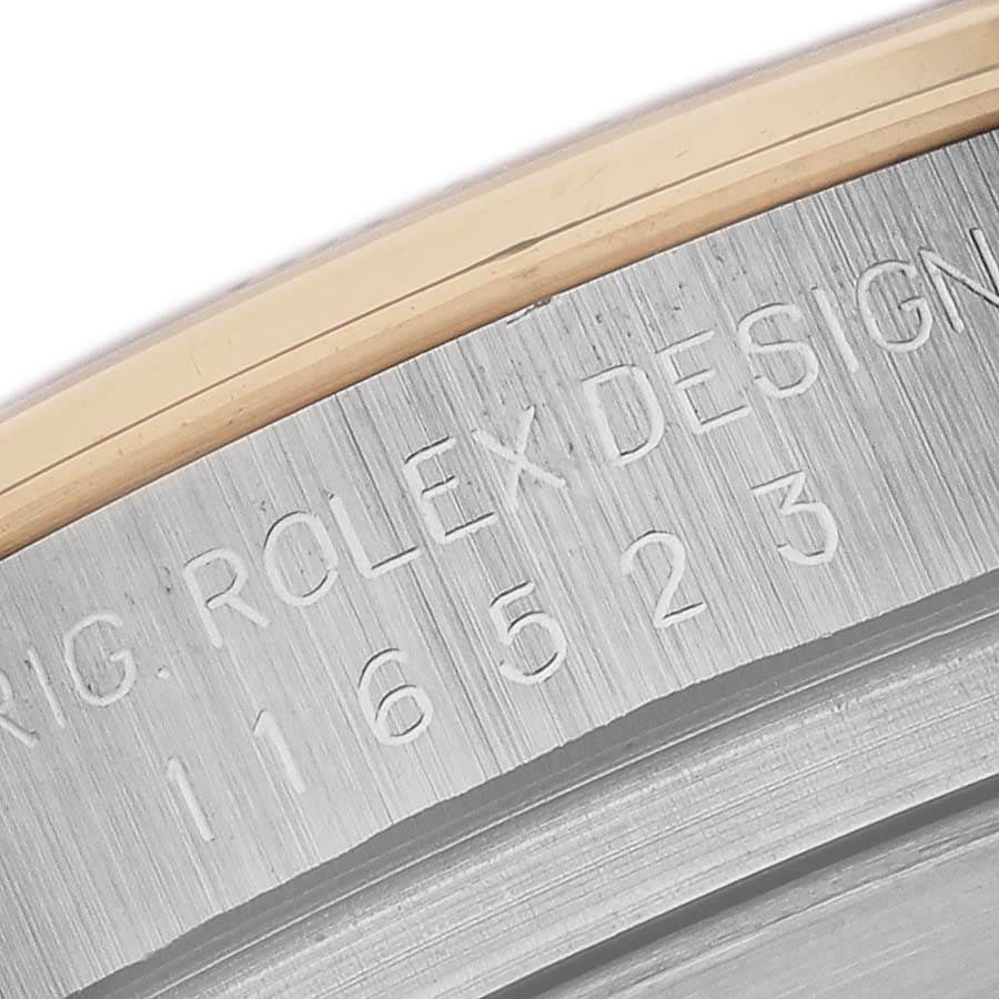 The image shows a close-up of the engraved inner rim of a Rolex Daytona 116523 Men
s Steel and Gold (two tone) White Dial 116523 Men
s Steel and Gold (two tone) White Dial watch case.