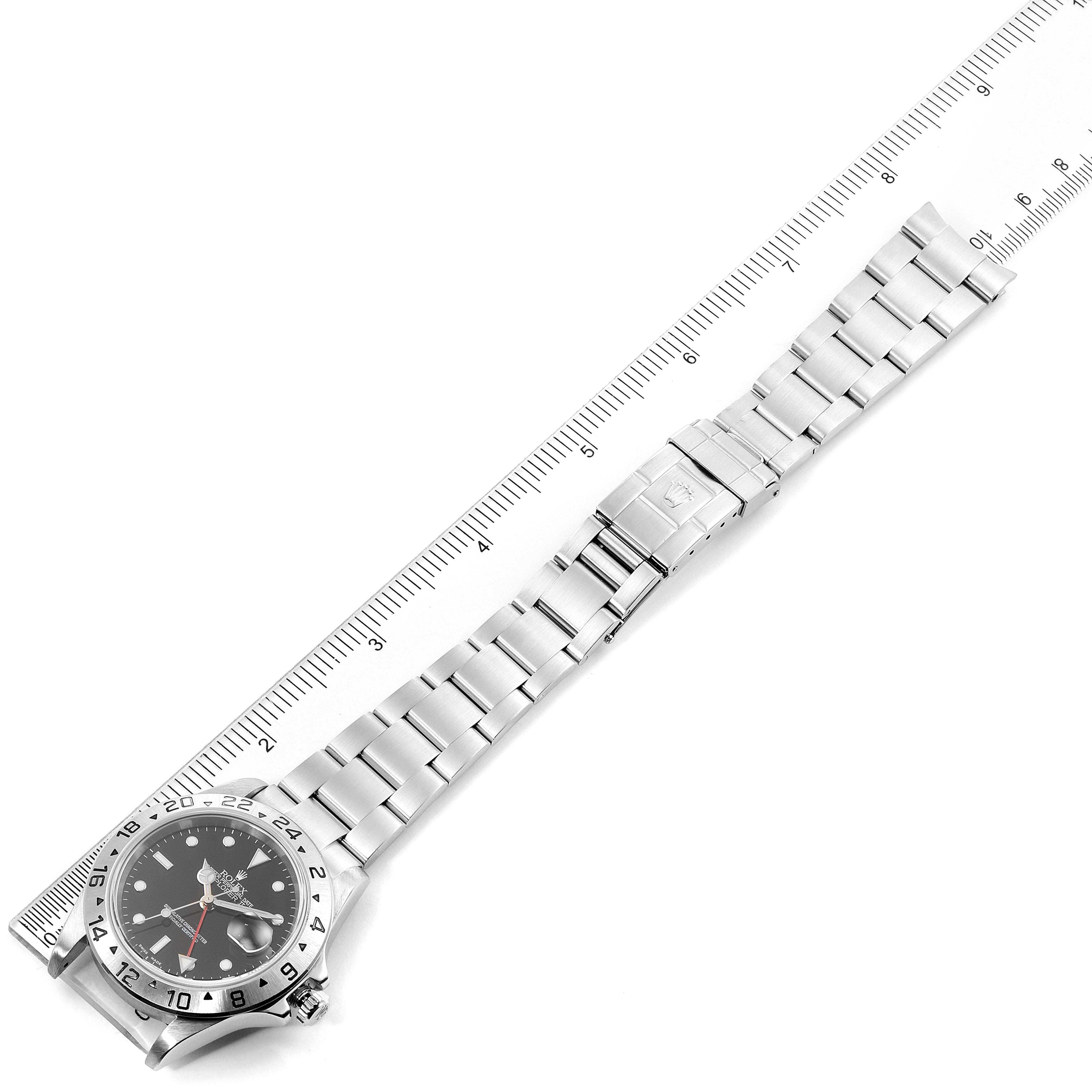 The Rolex Explorer 16570 Men
s Stainless Steel Black Dial 16570 Men
s Stainless Steel Black Dial watch is shown from a top-down angle, displaying the face, bezel, bracelet, and clasp alongside a ruler.