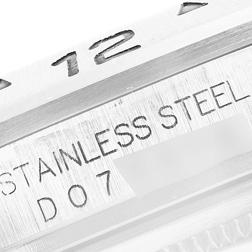 This close-up image of a Rolex Explorer 16570 Men
s Stainless Steel Black Dial 16570 Men
s Stainless Steel Black Dial shows part of the bezel, "12" numeral, and engraving with "STAINLESS STEEL D07".