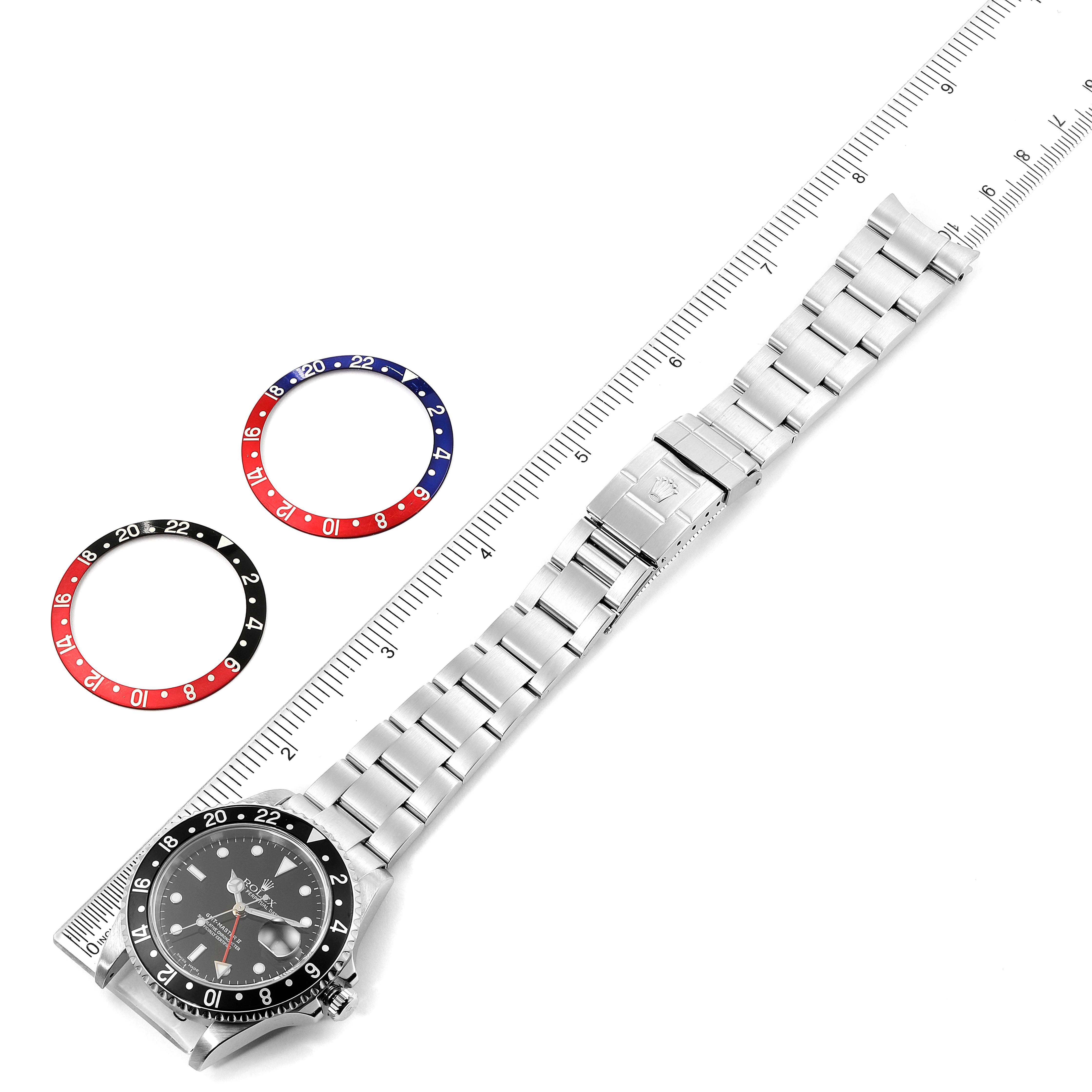 The image shows a Rolex GMT-Master 16710 Men
s Stainless Steel Black Dial 16710 Men
s Stainless Steel Black Dial watch, its bracelet, and two bezels, with a measurement scale alongside.
