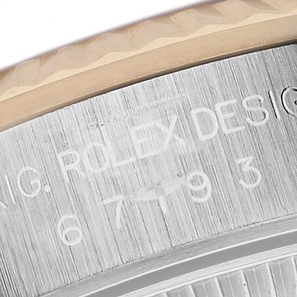 The image shows a close-up of the Rolex Oyster Perpetual 67193 Women's Steel and Gold (two tone) Champagne Dial 67193 Women's Steel and Gold (two tone) Champagne Dial's engraved case edge and part of the bezel.