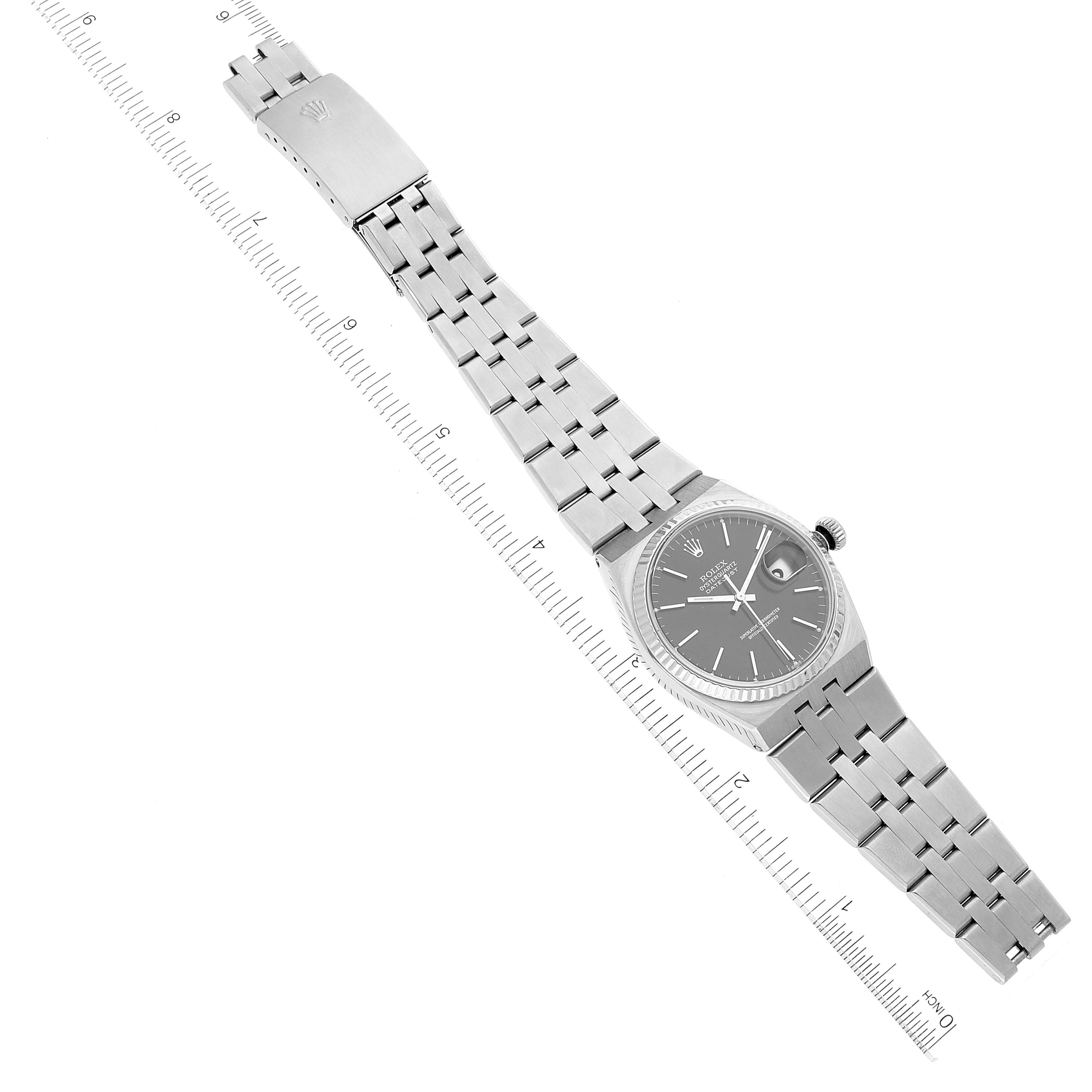 The image shows a top-down view of a Rolex Oysterquartz 17014 Men's Stainless Steel Black Dial 17014 Men's Stainless Steel Black Dial watch with its bracelet fully extended alongside a measuring ruler.