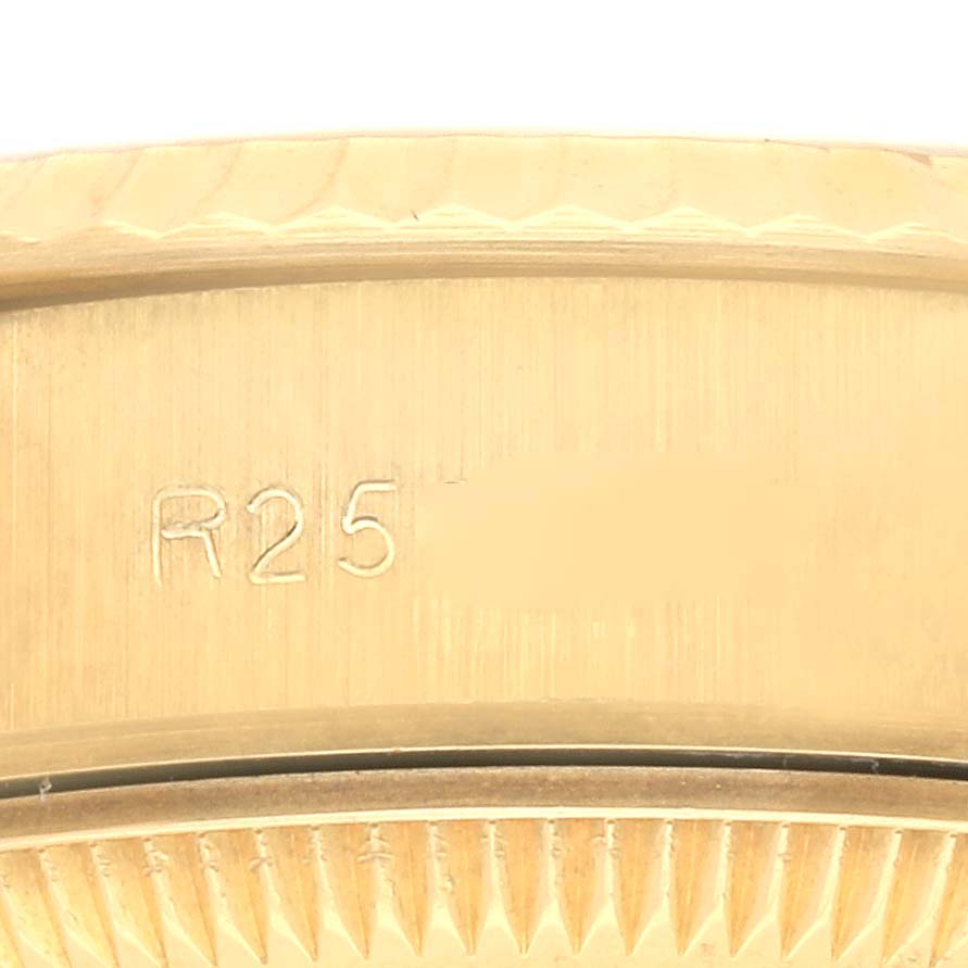 The image shows a close-up of the Rolex President 69178 Women's Yellow Gold Champagne Dial 69178 Women's Yellow Gold Champagne Dial model's watch bezel, highlighting its engravings and fluted edge.