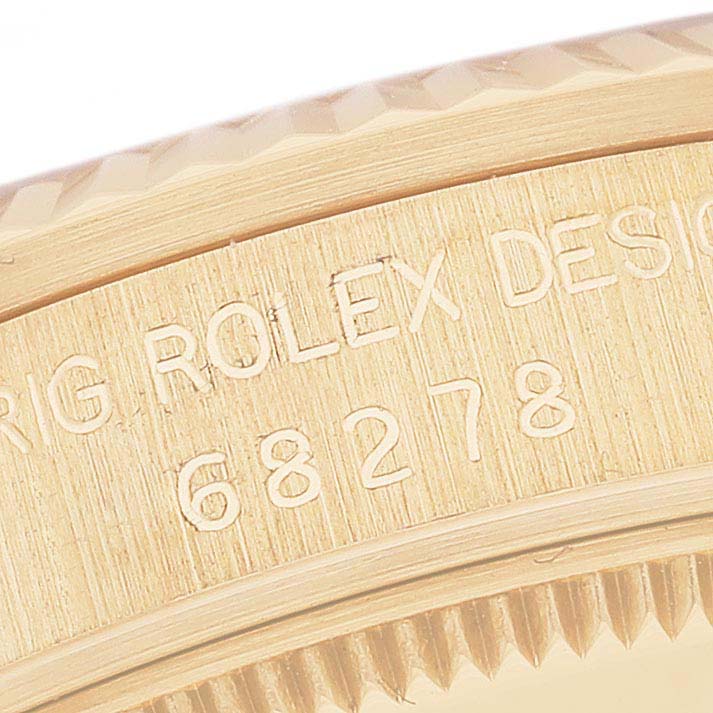 This image shows a close-up of the case and bezel of a Rolex President 68278 Women's Yellow Gold White Dial 68278 Women's Yellow Gold White Dial model, highlighting the engraved text and serial number.