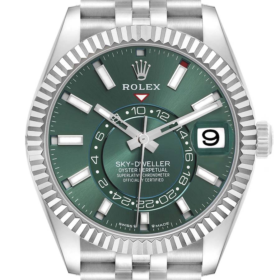 The Rolex Sky-Dweller watch is shown from a front angle, displaying its green dial, date window, fluted bezel, and bracelet.