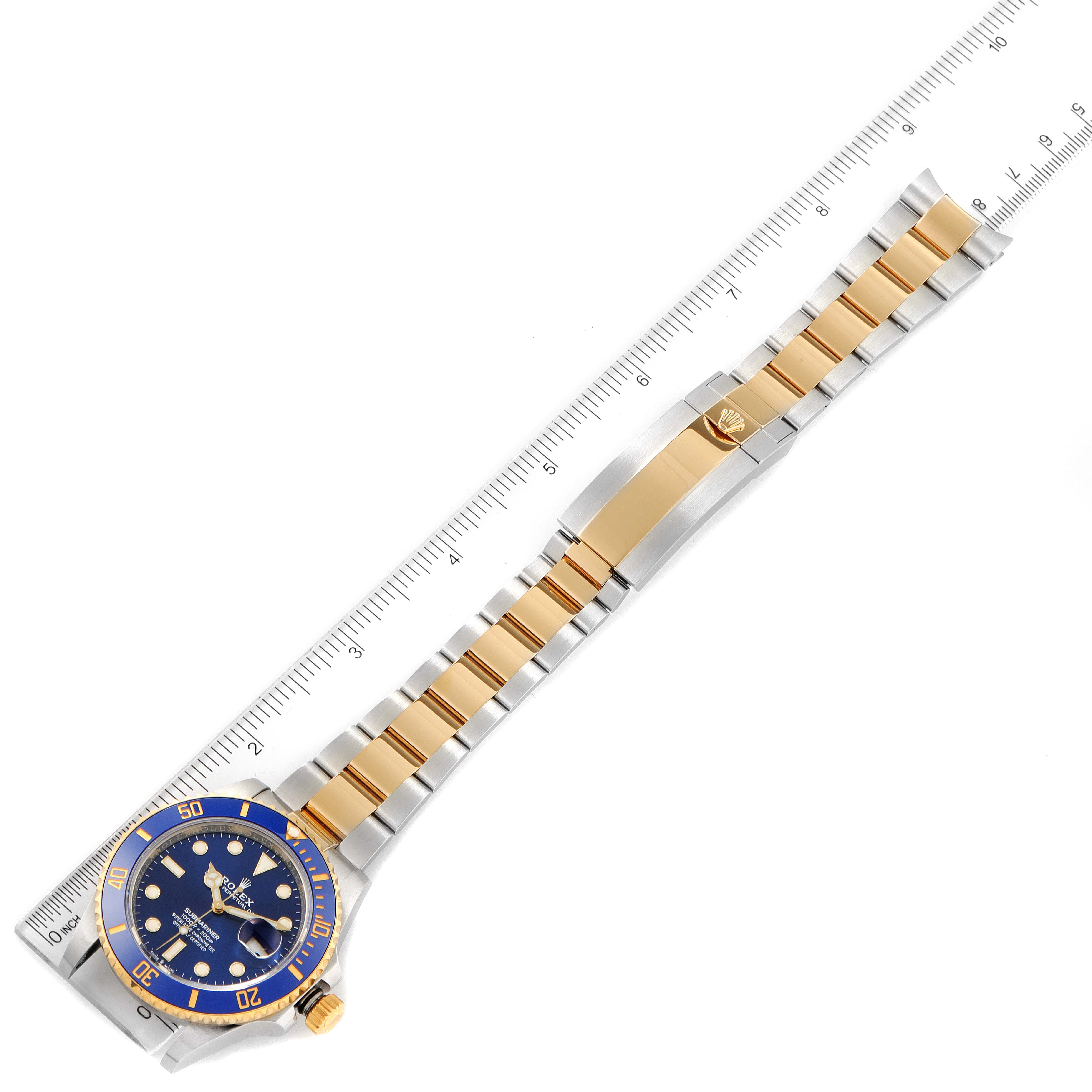 The image shows a top view of a Rolex Submariner 126613 Men
s Steel and Gold (two tone) Blue Dial 126613 Men
s Steel and Gold (two tone) Blue Dial watch, displaying its blue dial, bezel, and bracelet fully extended next to a ruler.