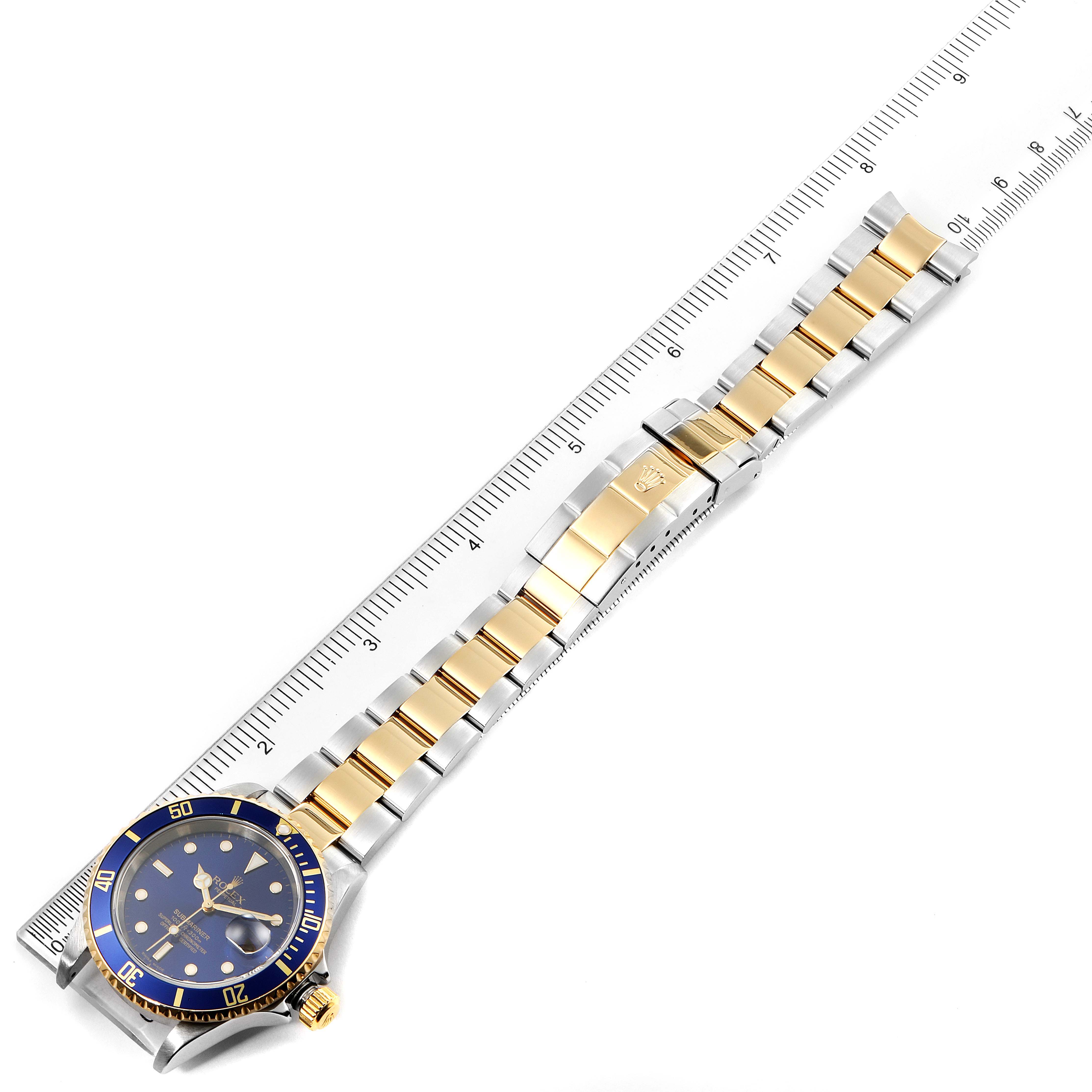 The image shows a Rolex Submariner 16613 Men's Steel and Gold (two tone) Blue Dial 16613 Men's Steel and Gold (two tone) Blue Dial watch laid flat, highlighting the blue and gold bezel, dial, and two-tone bracelet.