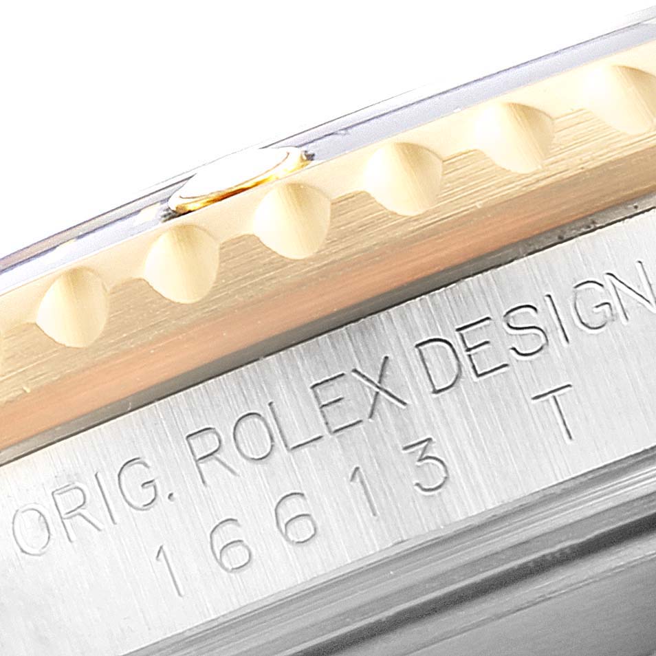 This close-up photo of a Rolex Submariner 16613 Men's Steel and Gold (two tone) Blue Dial 16613 Men's Steel and Gold (two tone) Blue Dial watch shows part of the bezel and the engraved model and brand on the case.