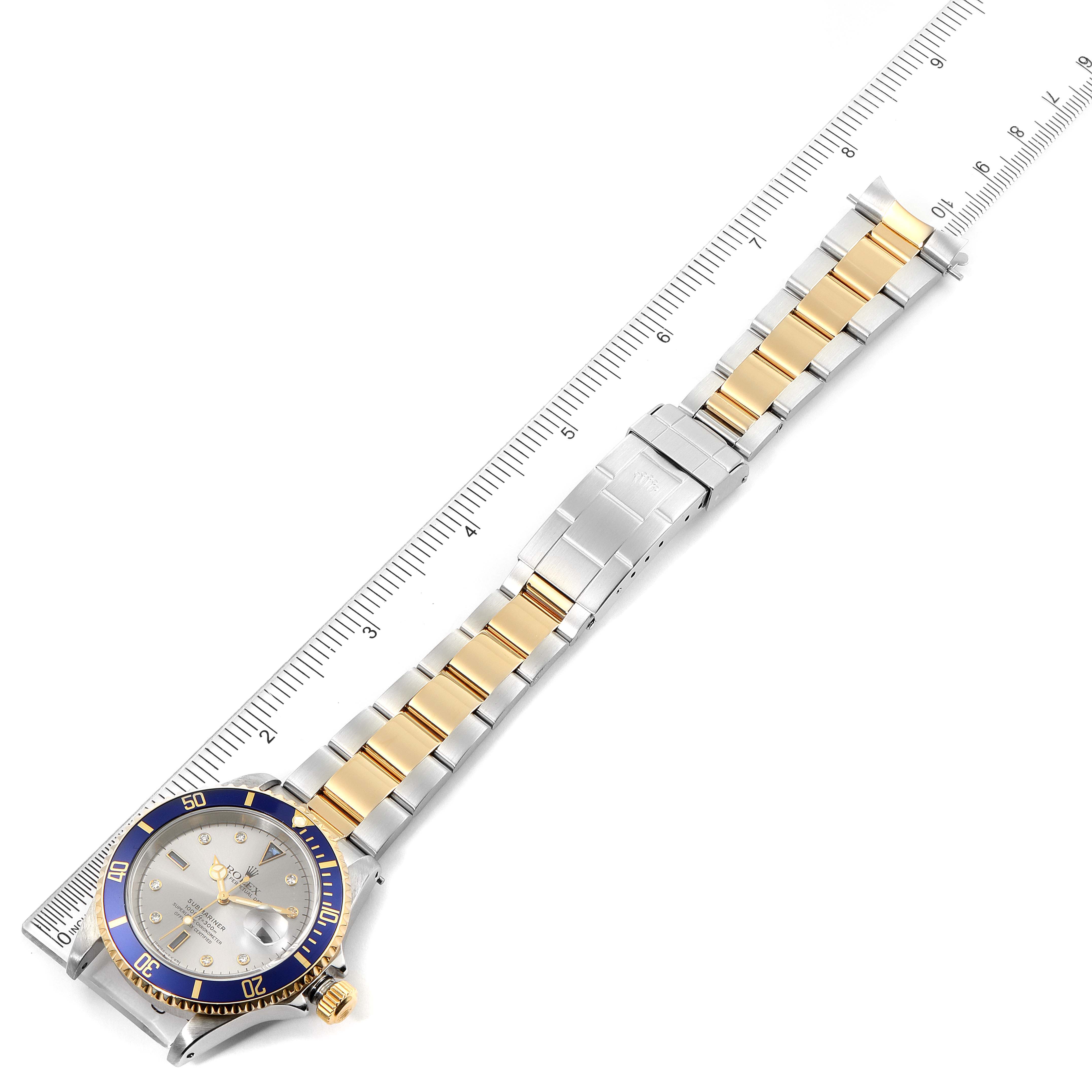 The image shows a top view of a Rolex Submariner 16613 Men's Steel and Gold (two tone) Grey Dial 16613 Men's Steel and Gold (two tone) Grey Dial watch with a two-tone metal bracelet and a blue bezel.