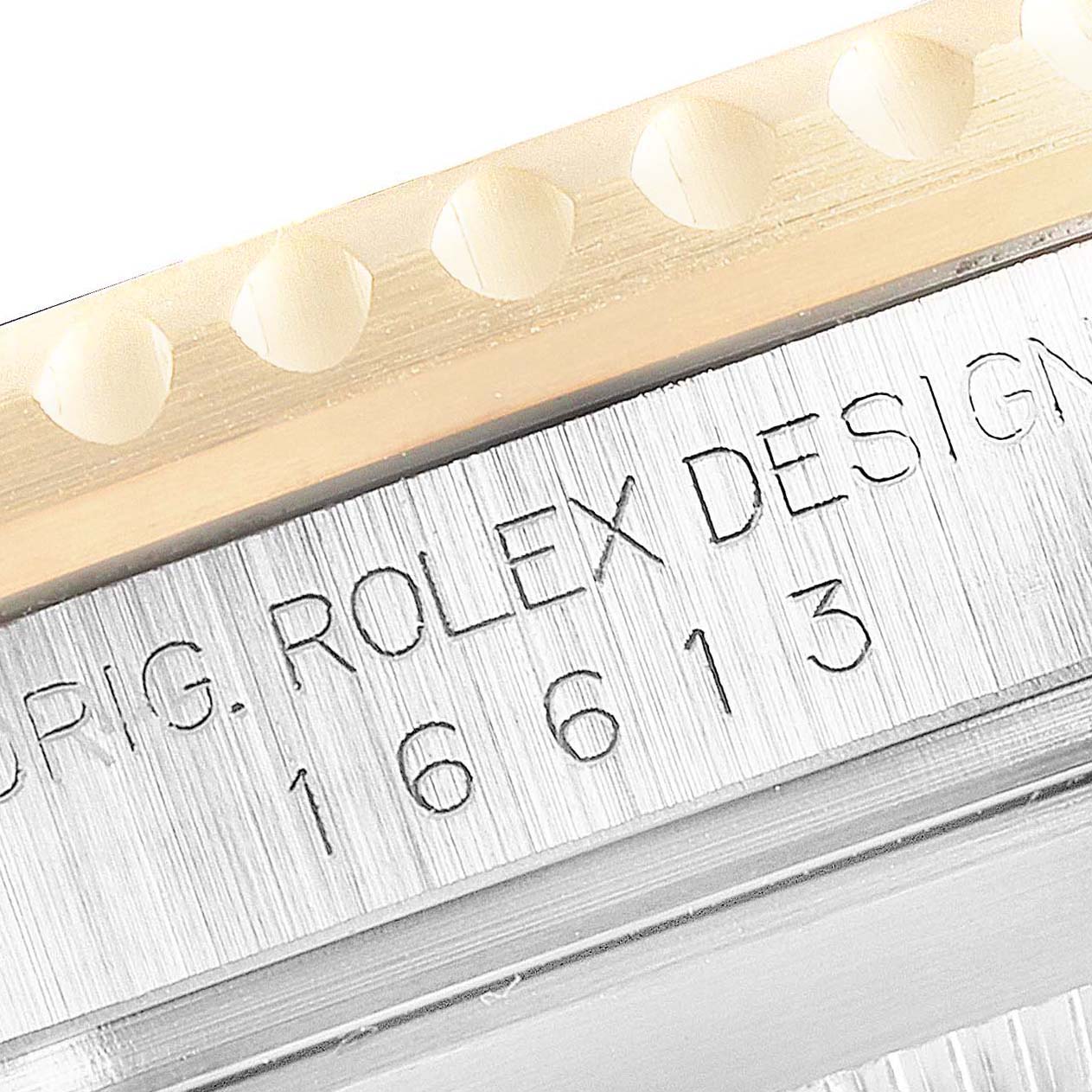 The image shows a close-up of the side of a Rolex Submariner 16613 Men's Steel and Gold (two tone) Grey Dial 16613 Men's Steel and Gold (two tone) Grey Dial watch, highlighting the engraved model number 16613 and part of the bezel.