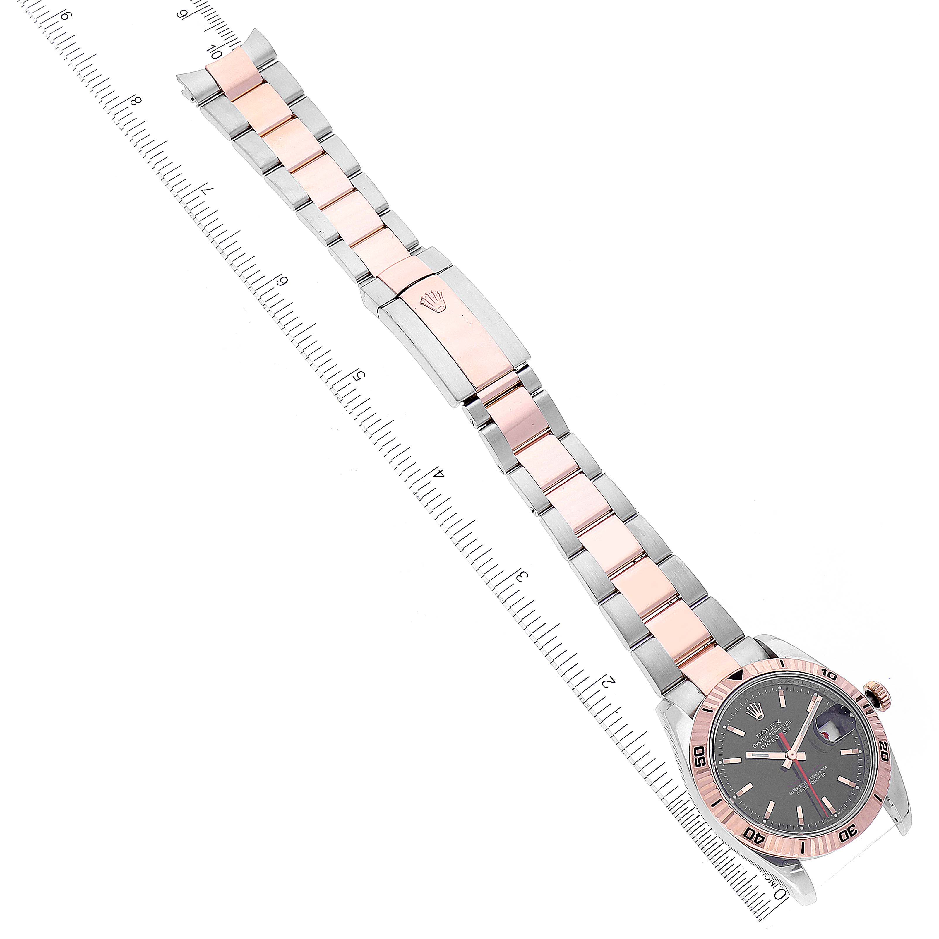 The image shows a full view of a Rolex Turn-o-Graph 116261 Men
s Steel and Gold (two tone) Black Dial 116261 Men
s Steel and Gold (two tone) Black Dial watch laid flat, displaying its face and two-tone metal bracelet against a ruler.