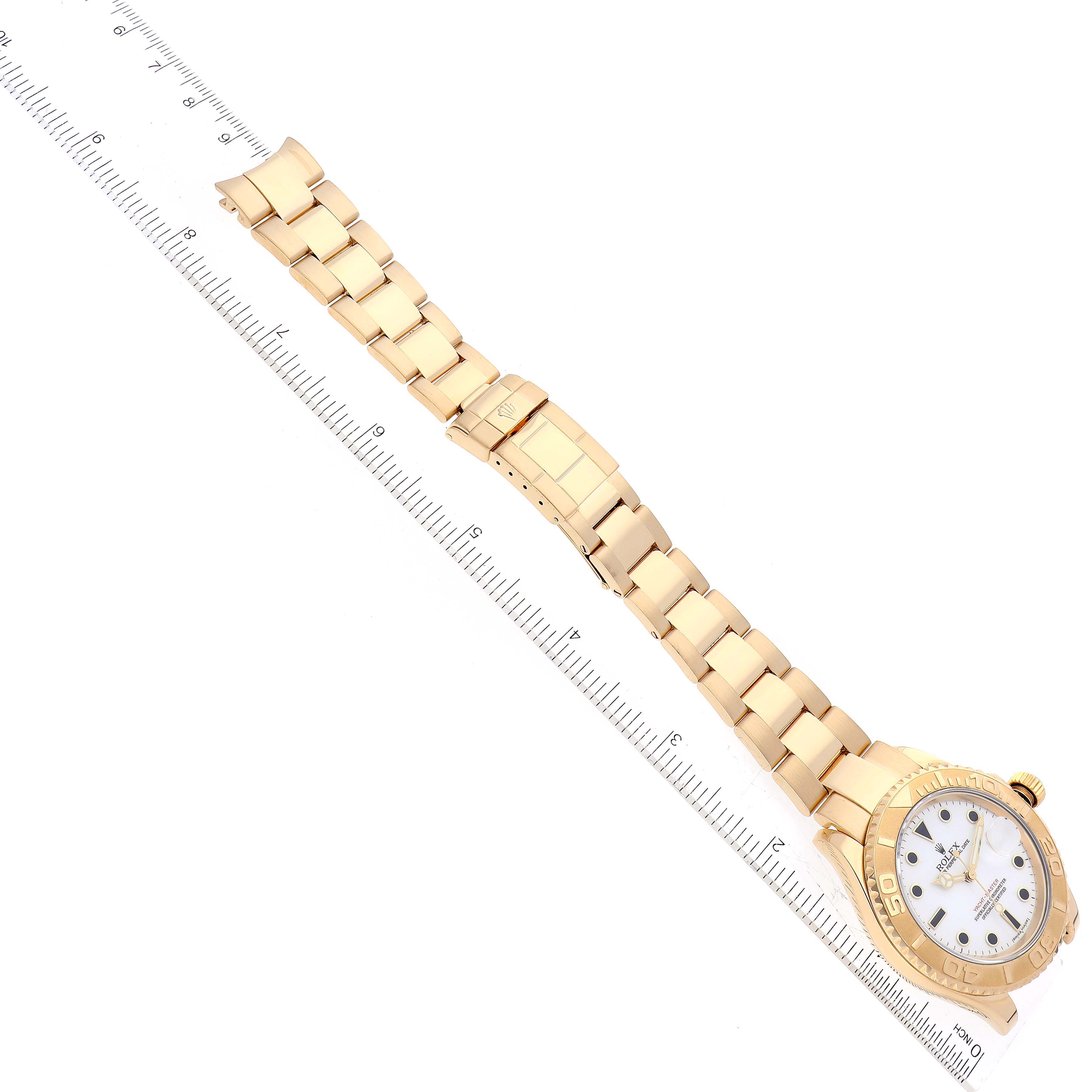 The Rolex Yacht-Master 16628 Men's Yellow Gold White Dial 16628 Men's Yellow Gold White Dial watch is shown flat with its band extended, including the face, bezel, and bracelet against a ruler for scale.