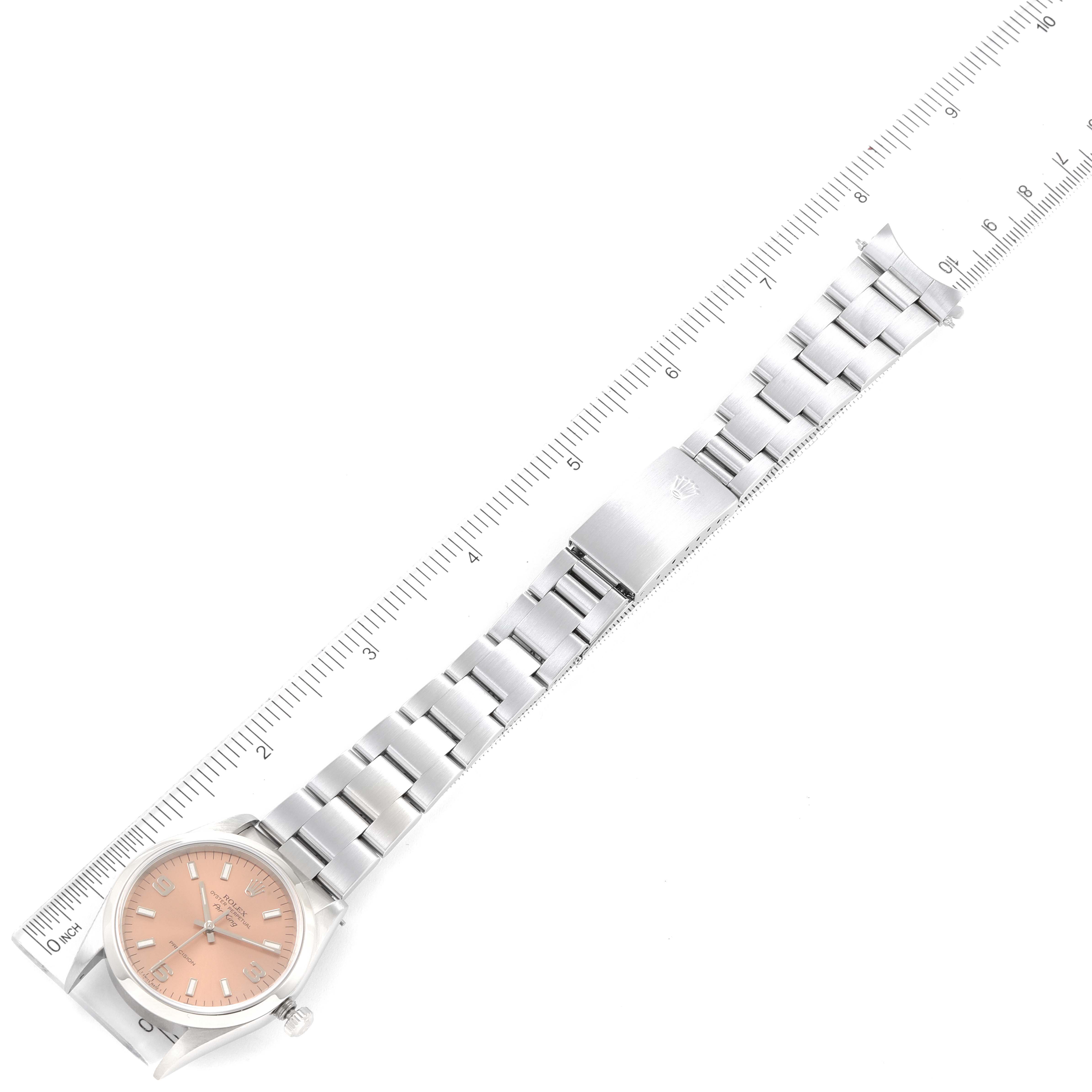 This image shows a Rolex Air-King 14000 Men's Stainless Steel Pink Dial 14000 Men's Stainless Steel Pink Dial watch laid flat alongside a ruler, highlighting its peach dial, stainless steel band, and clasp.